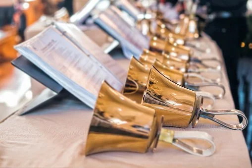 Golden wedding bells and a menu on a table at an event or celebration.