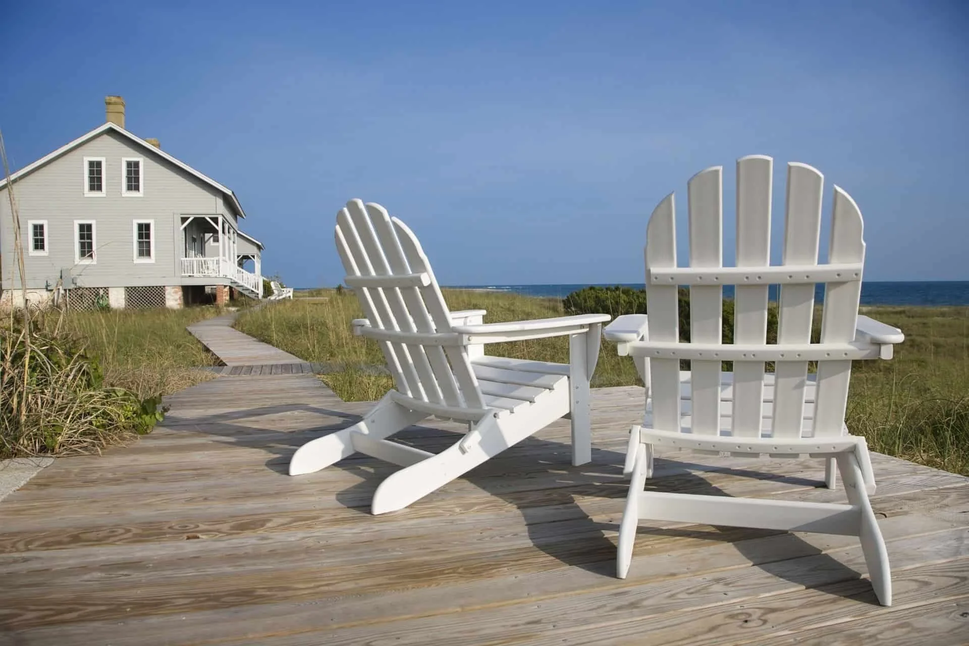 two beach chairs on the deck in front of the beach