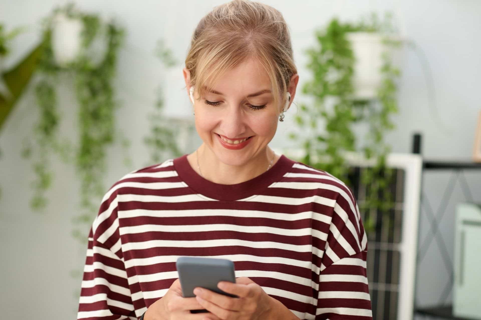 a women with ear buds in leaving a rental review on her phone