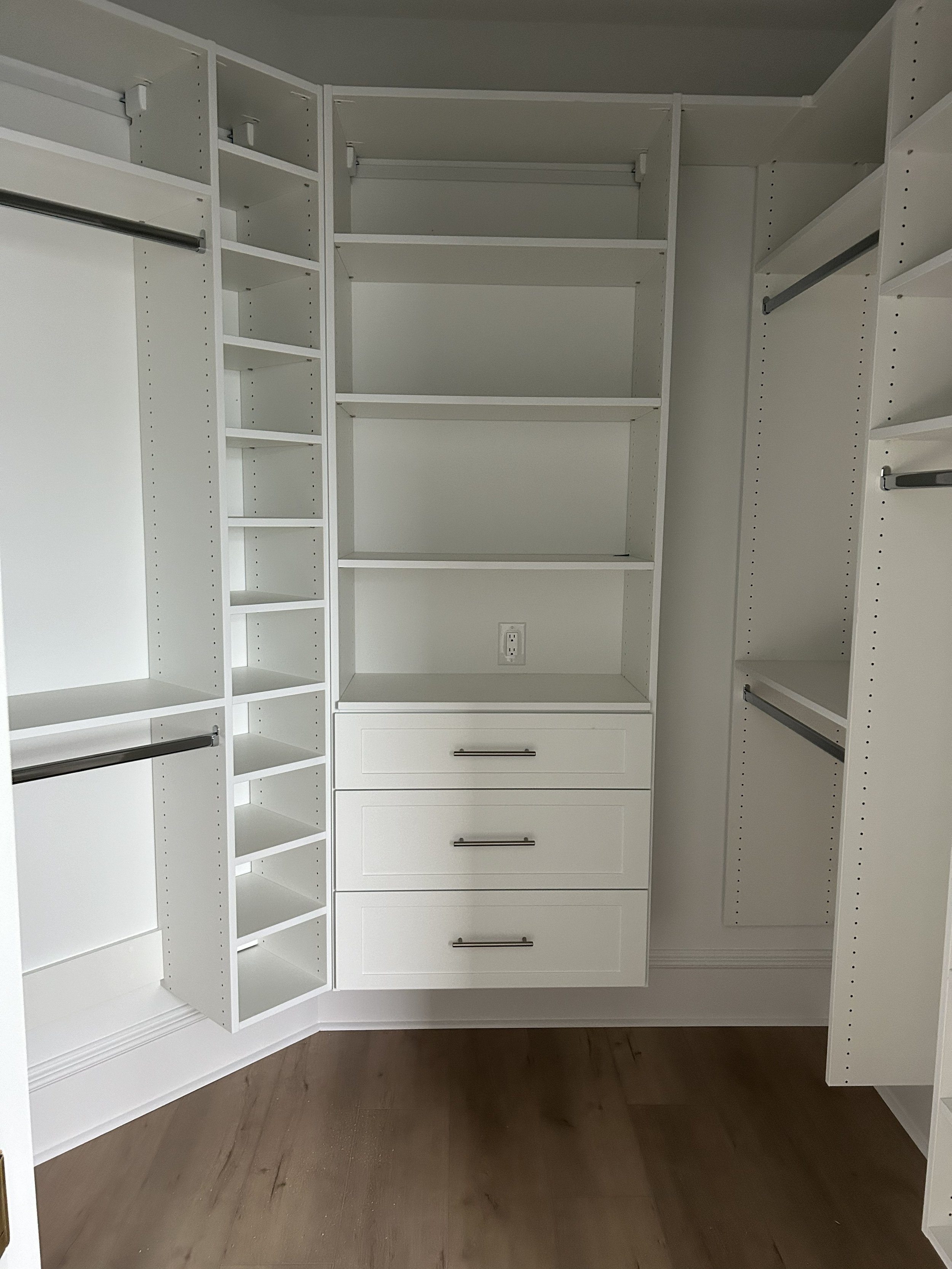 New home walk-in closet with shelves, drawers, and rods for hanging clothes.