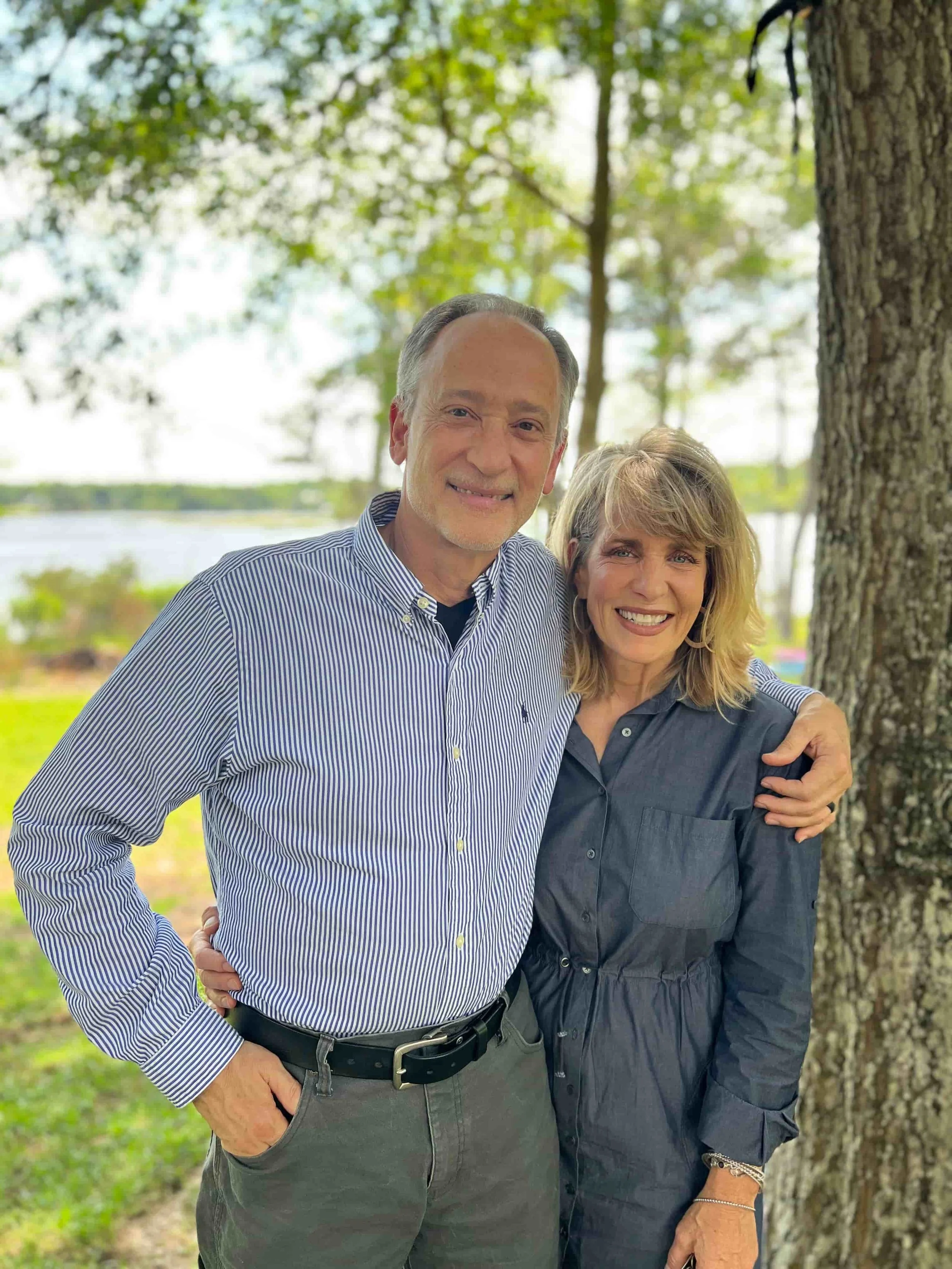 Tim Kathy Alexander standing near the water and next to a tree