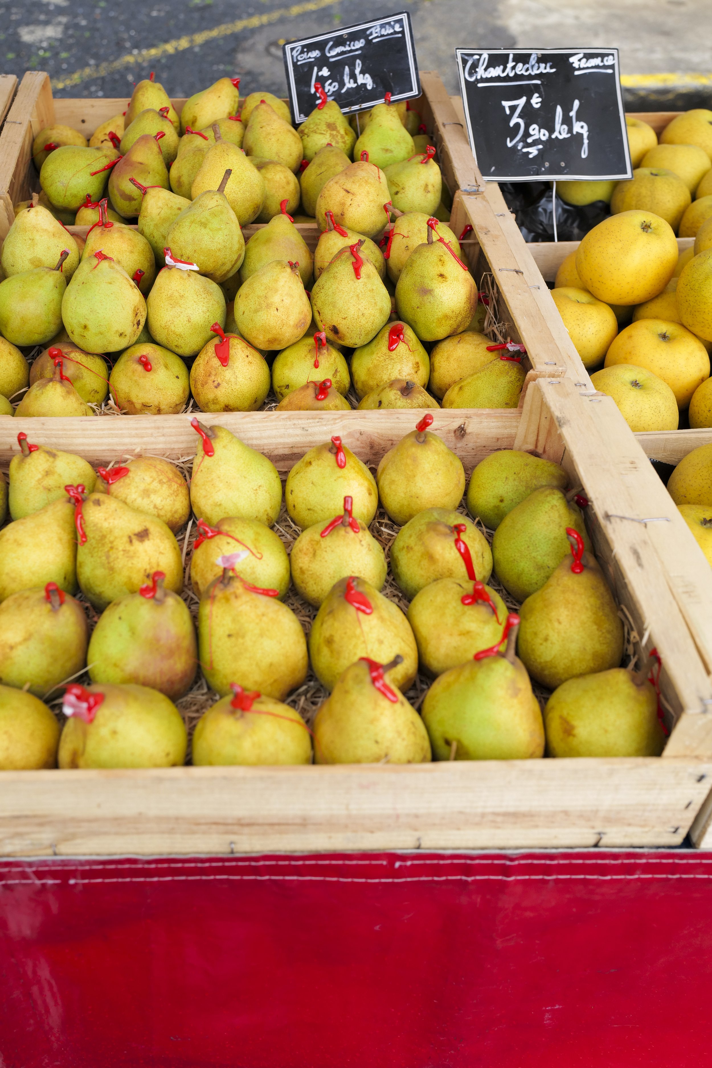 Display of yellow pears for sale at a market, with handwritten signs indicating the type and price.