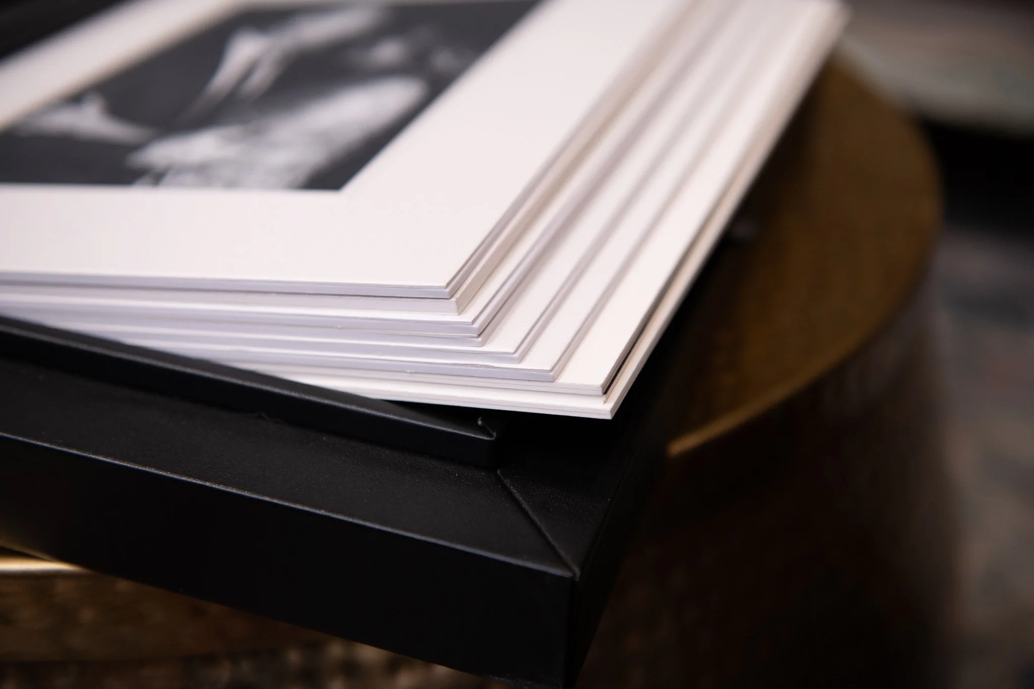 Open photo album with black cover resting on a round table, displaying a black and white photograph of a person.