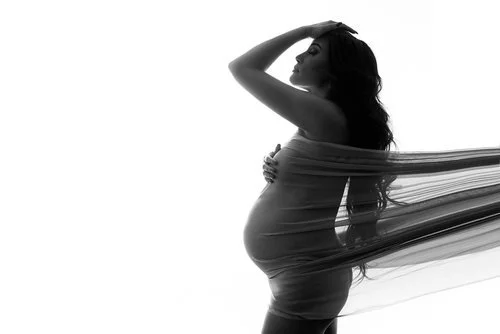 Silhouette of a pregnant woman with flowing fabric, in black and white.