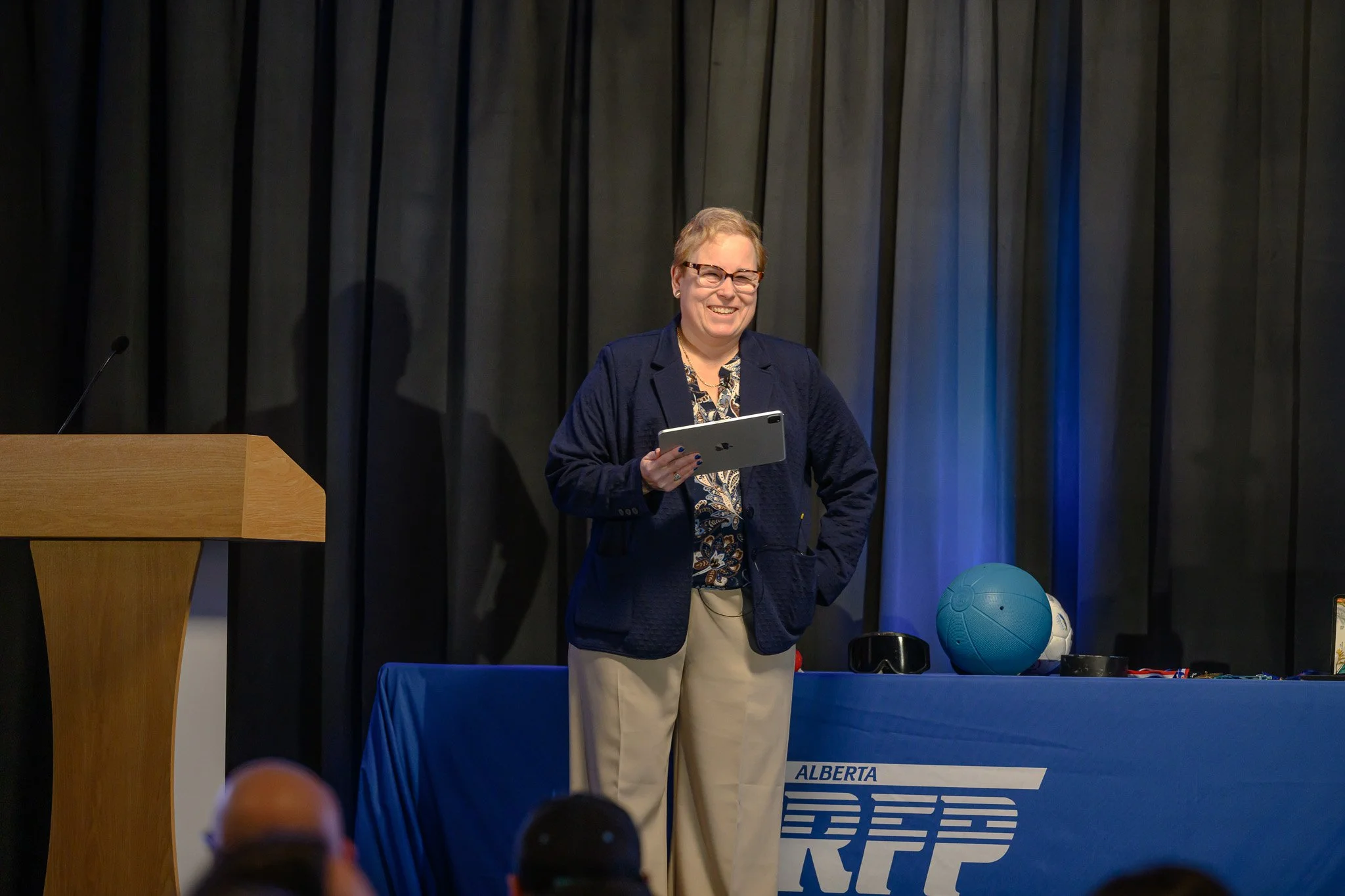 Carrie presenting at AARFP 2026 with a display table with adapted balls behind her.