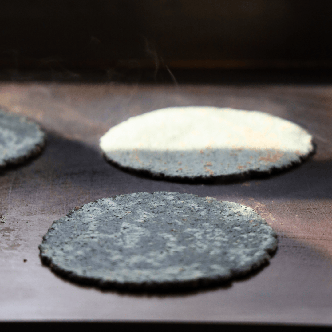 Chicheria blue corn tortillas on grill top.png