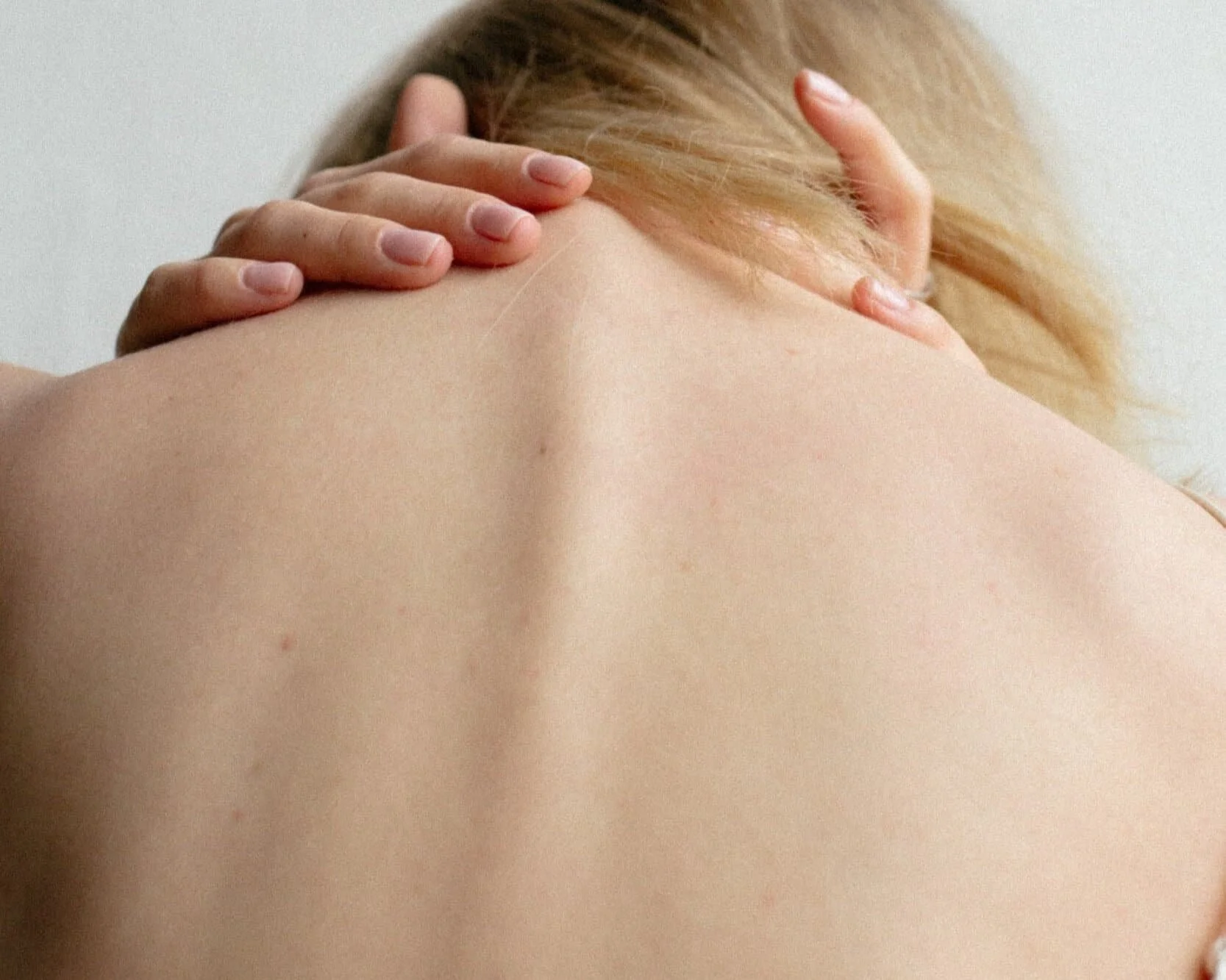 Woman touching spine reminiscent of scoliosis
