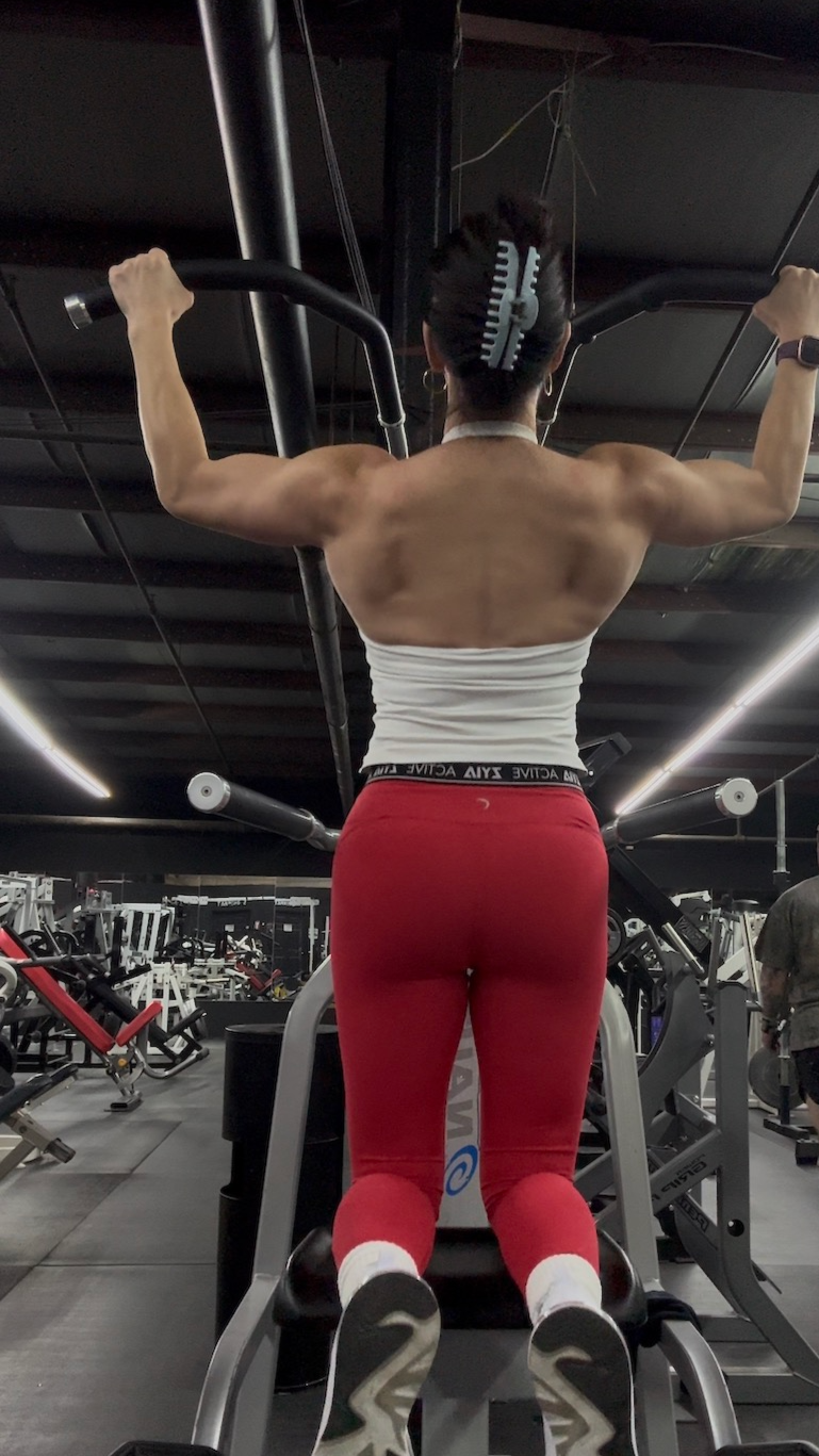 woman in white top and red pants doing a pullup