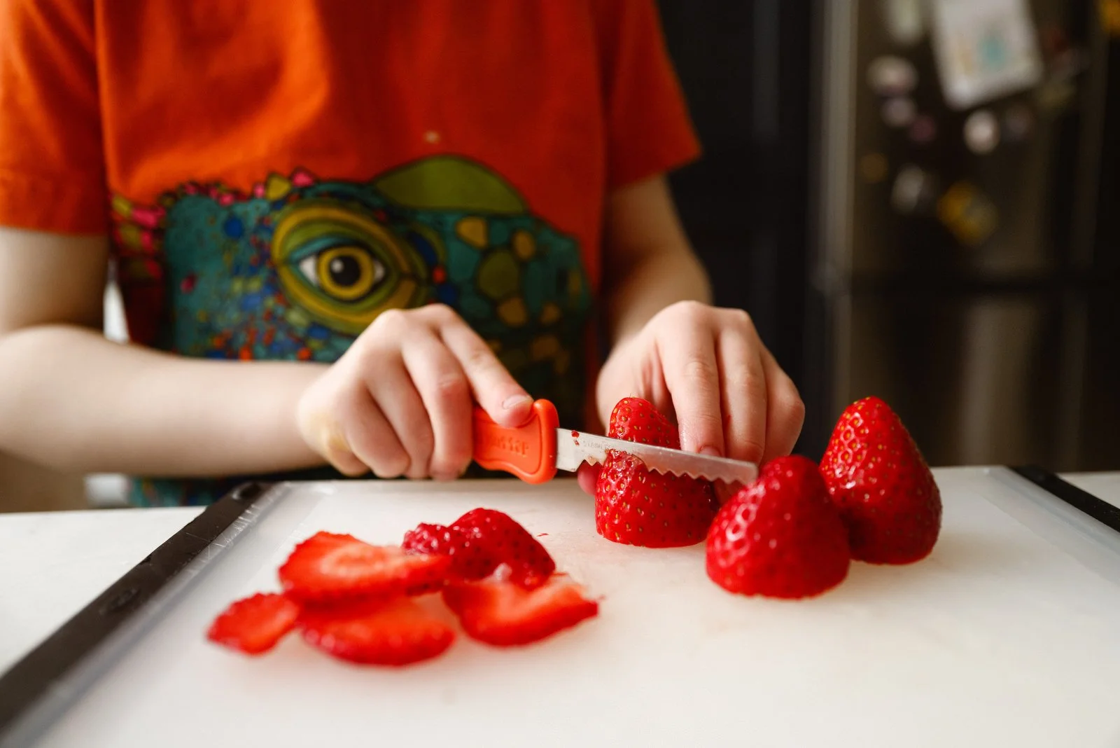 Person slicing strawberries on a cutting board.