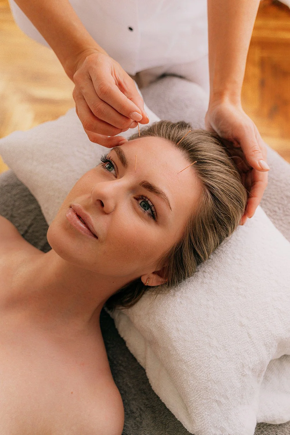 woman looking relaxed while receiving acupuncture facial treatment