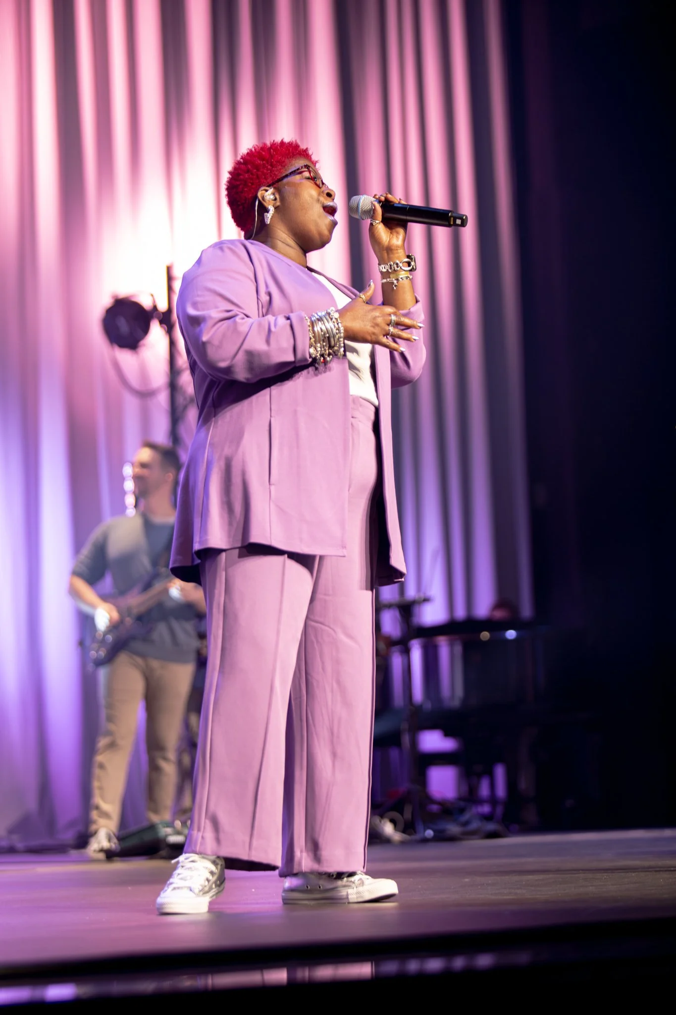 Singer in purple suit performing on stage with microphone