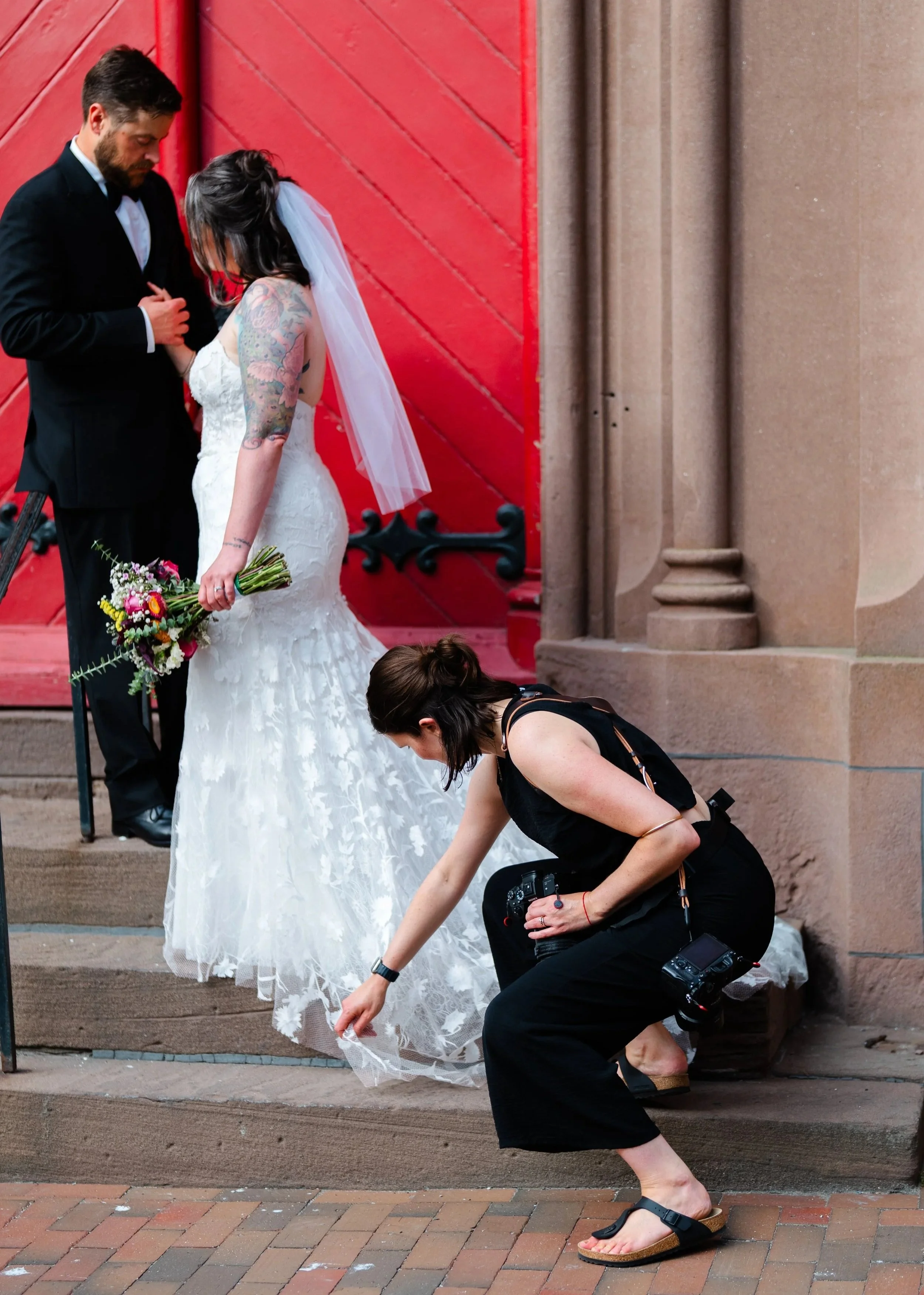 Julia Warner fixing a bride's dress in Portland, Maine of Warner Photography