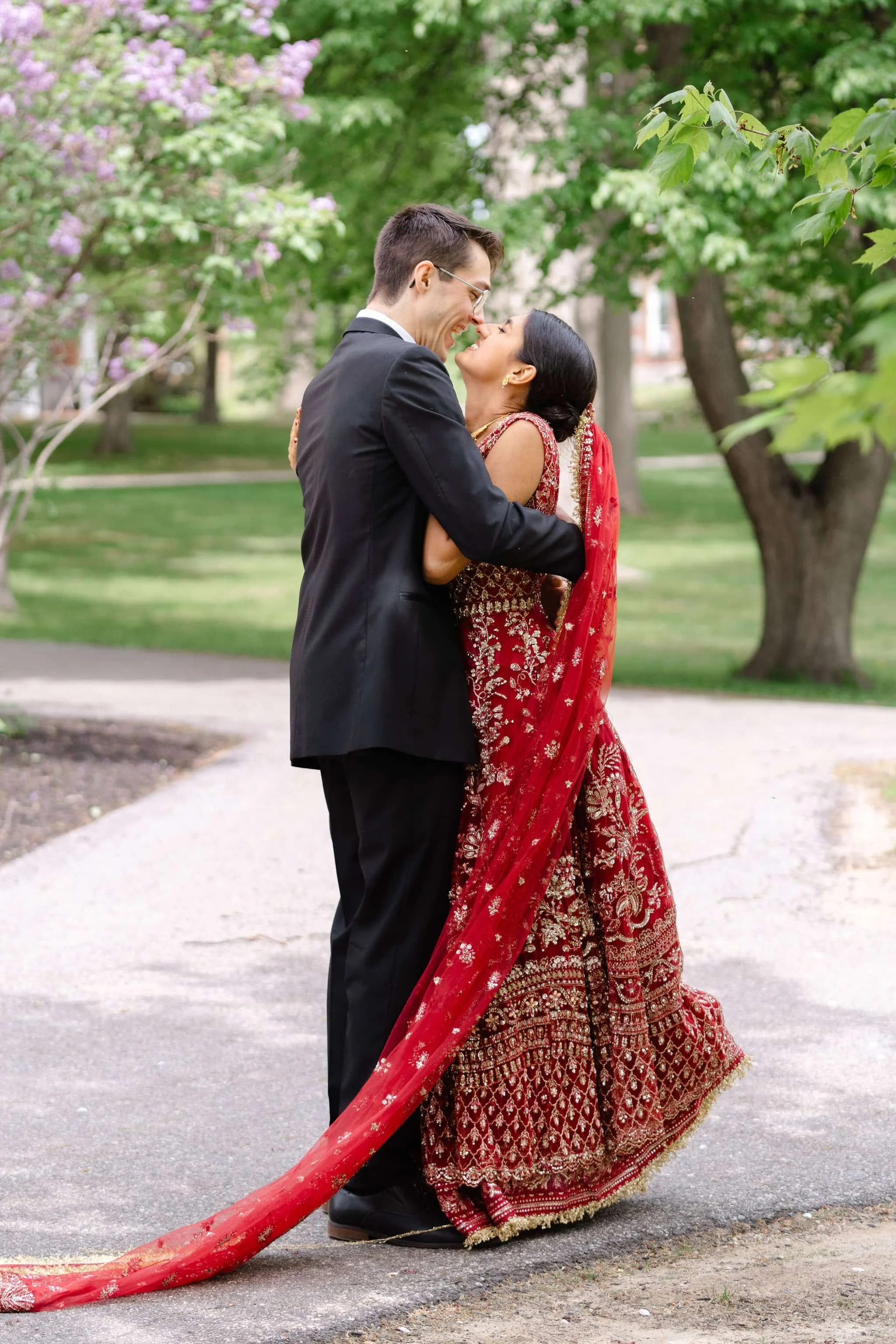 A couple appears to be at their Maine wedding, with the man in a dark suit and the woman in a white dress. They are smiling and looking at each other, captured by Maine wedding photographers Warner Photography