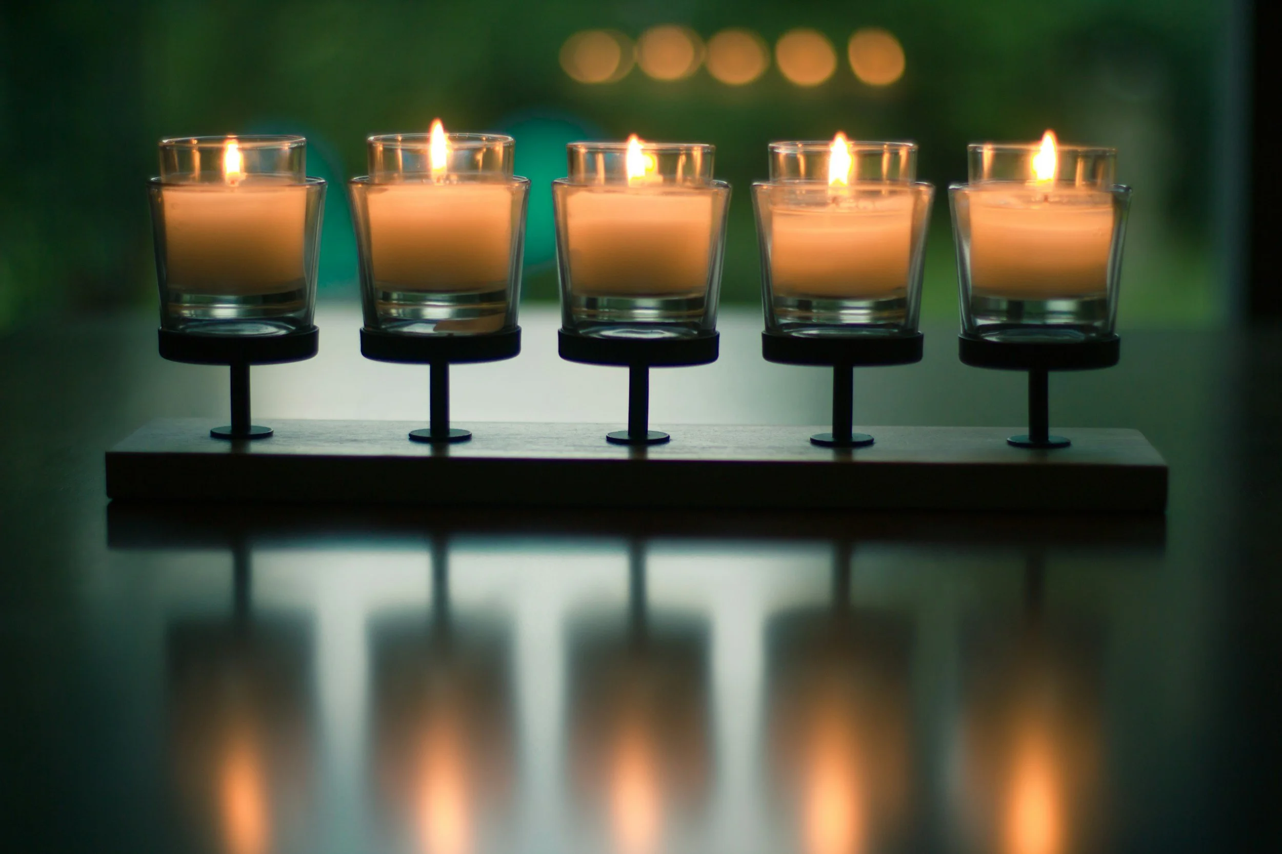 Five orange candles with green background representing the five koshas or the bio-psycho-social-spiritual model of well-being