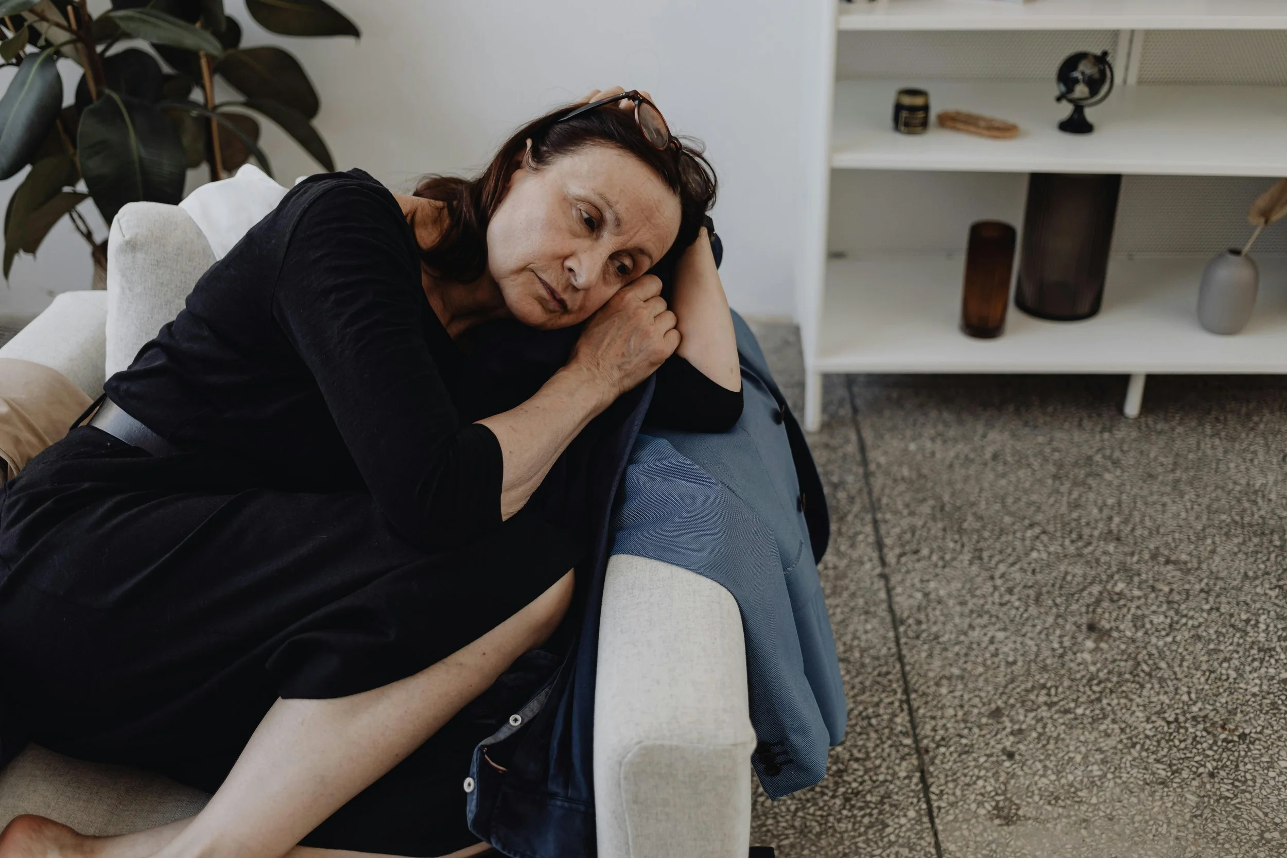 Woman sitting quietly on a couch, reflecting on her thoughts and emotions