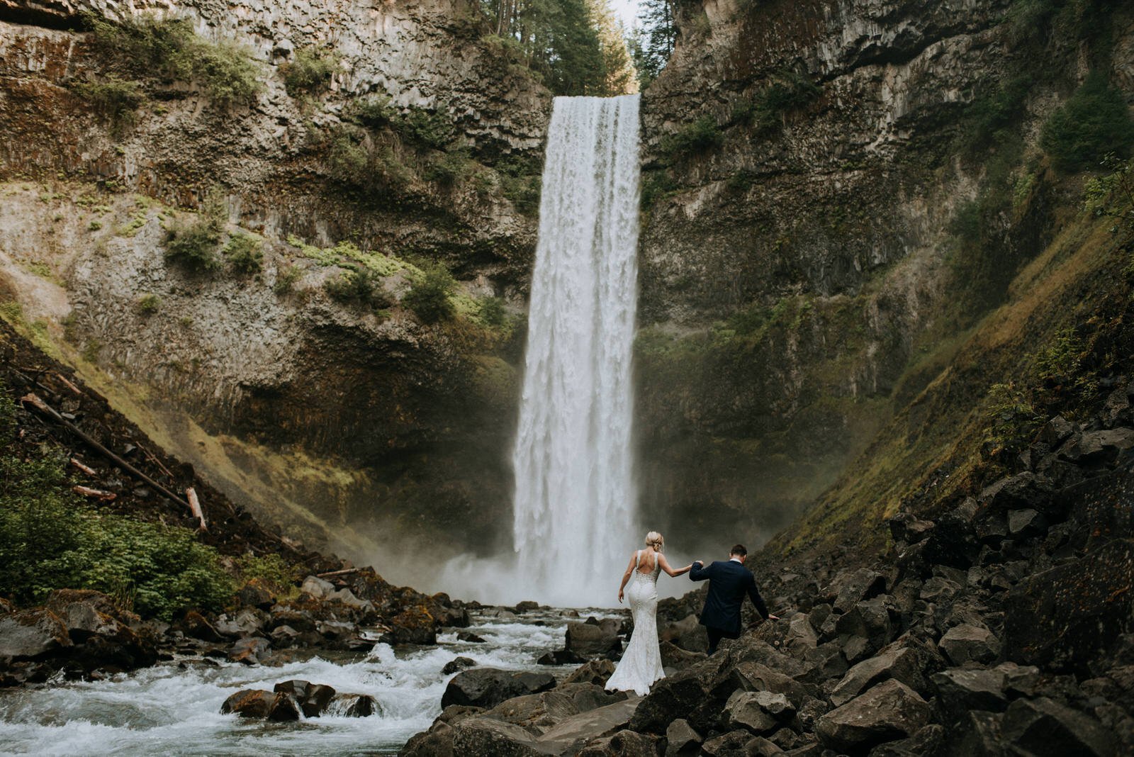 Bride and Groom walking towards waterfall 