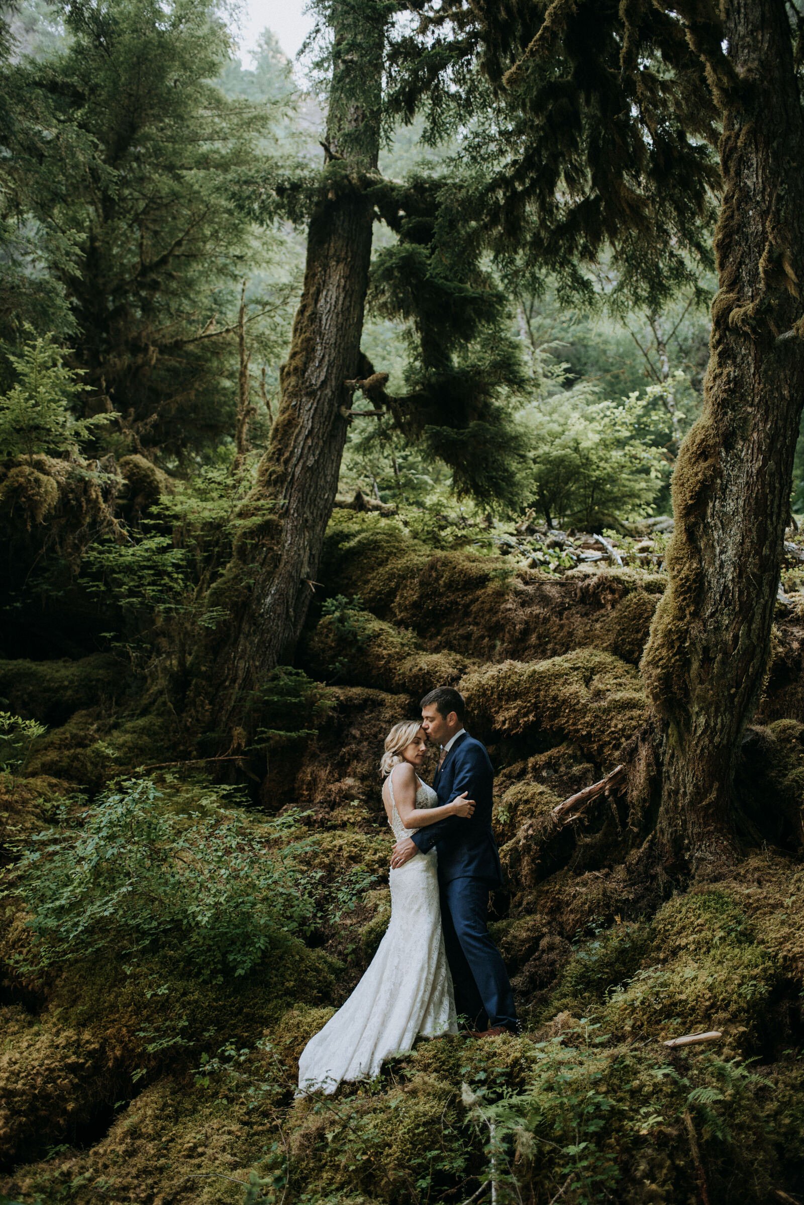 bride and groom in moss covered forest embracing