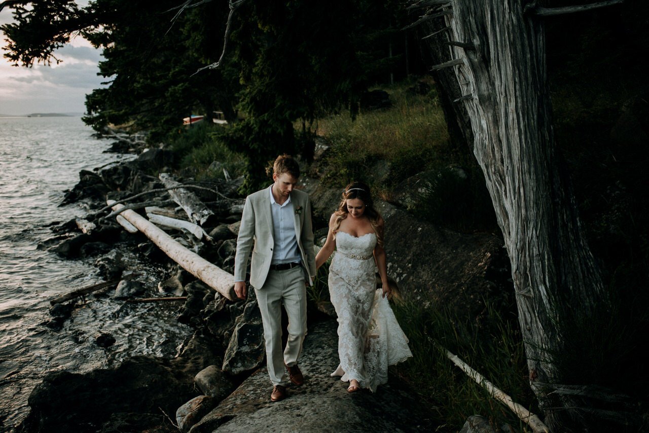 bride and groom holding hands walking on rock beach galiano island at sunset