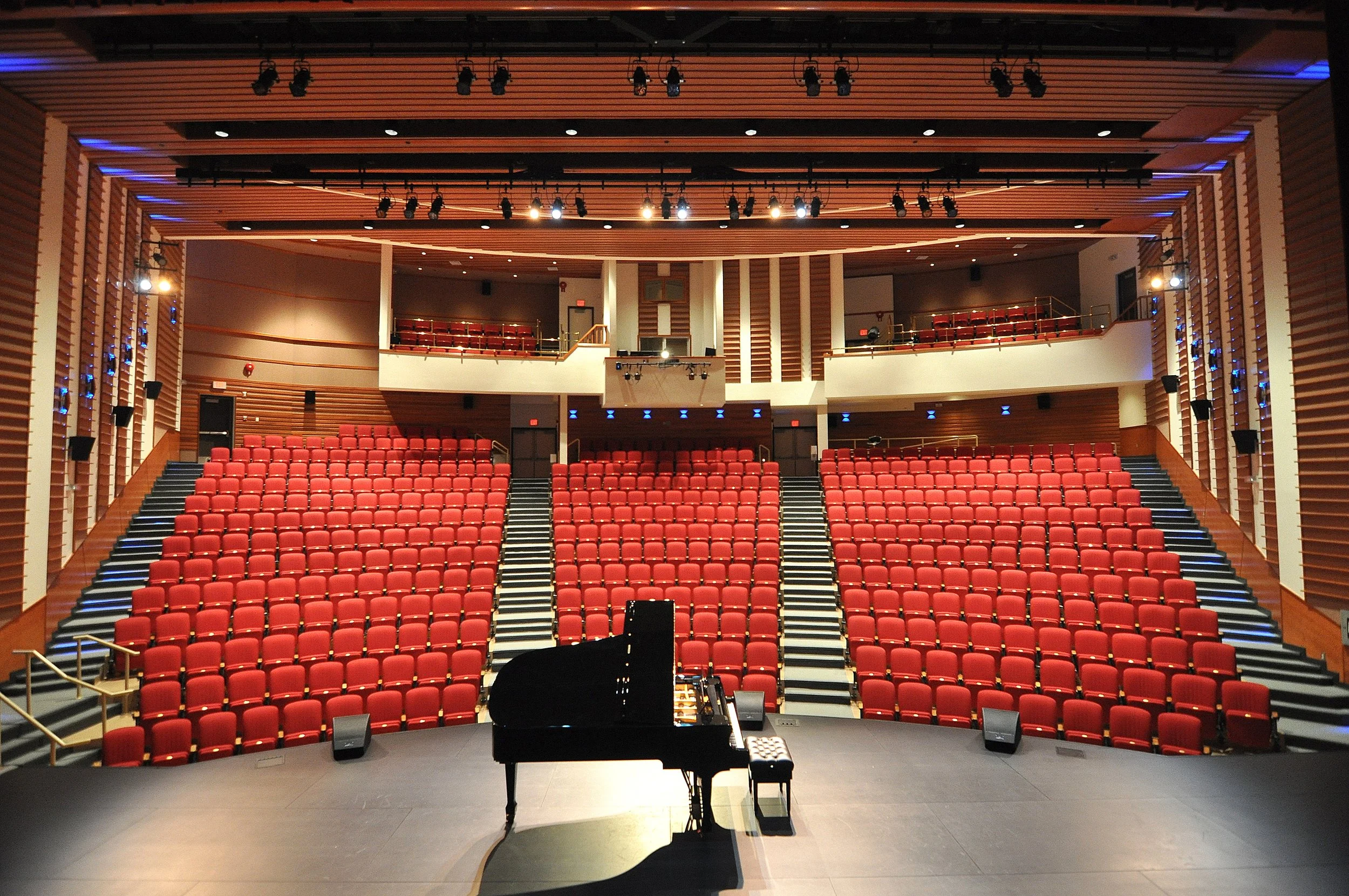 Red theater seats, and a modern auditorium interior with wooden accents and lighting.