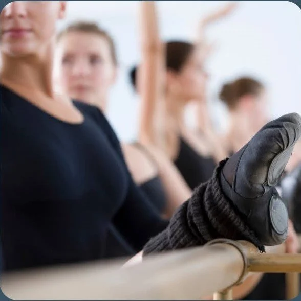 Ballet students practicing at a barre in a dance class