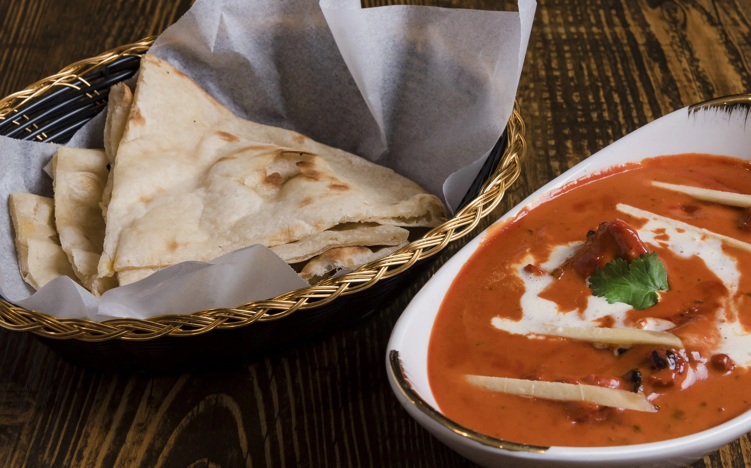 Basket of naan bread and a bowl of Butter Chicken