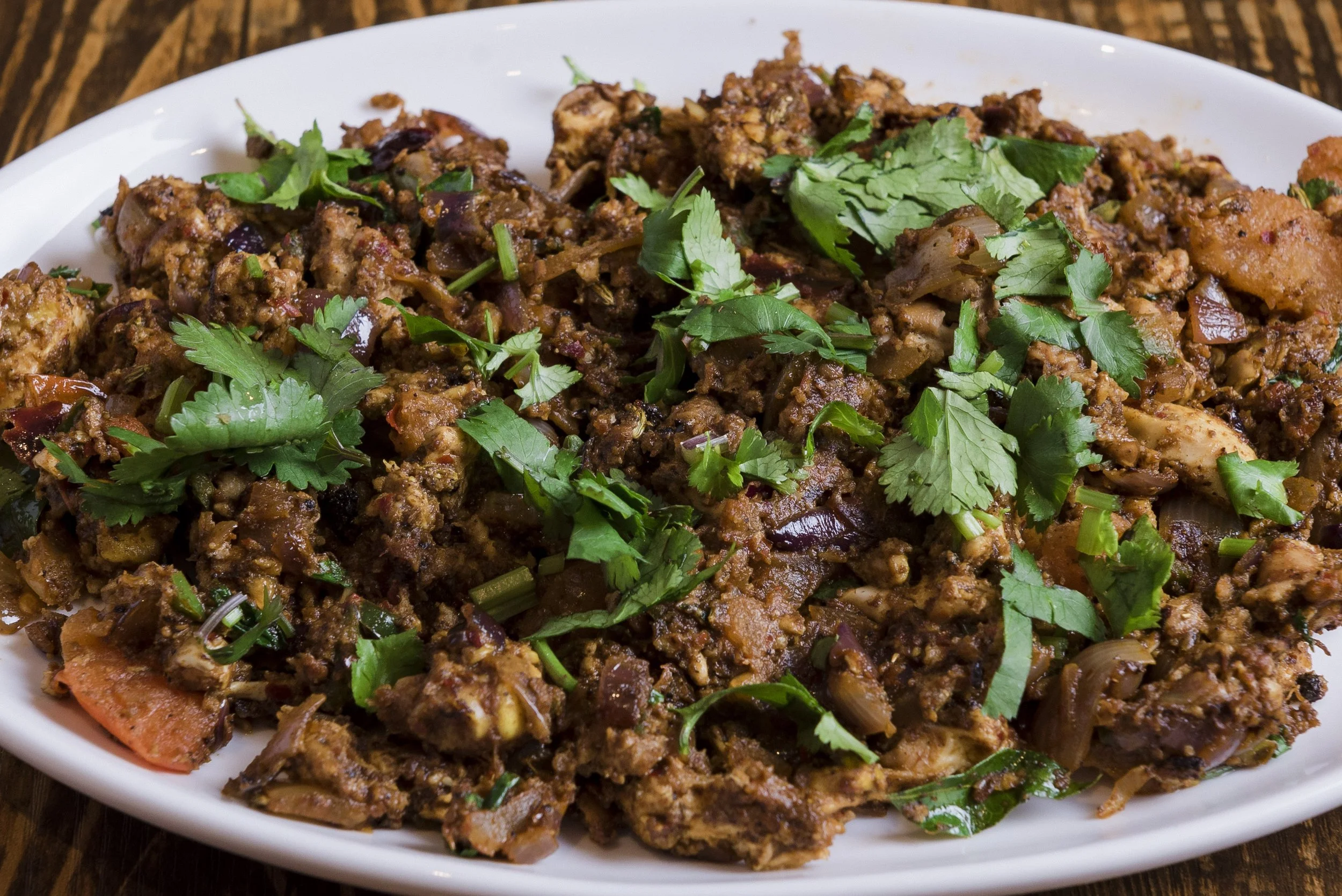 Plate of cooked meat and vegetables garnished with fresh cilantro.