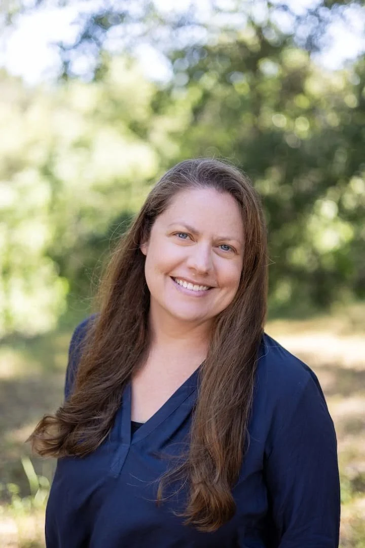 therapist with long hair and a blue top smiling