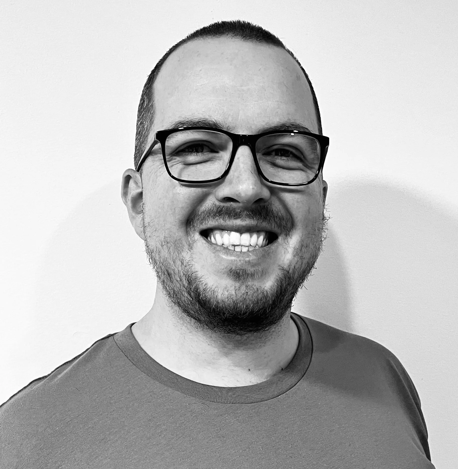 Black and white portrait of a smiling person wearing glasses.