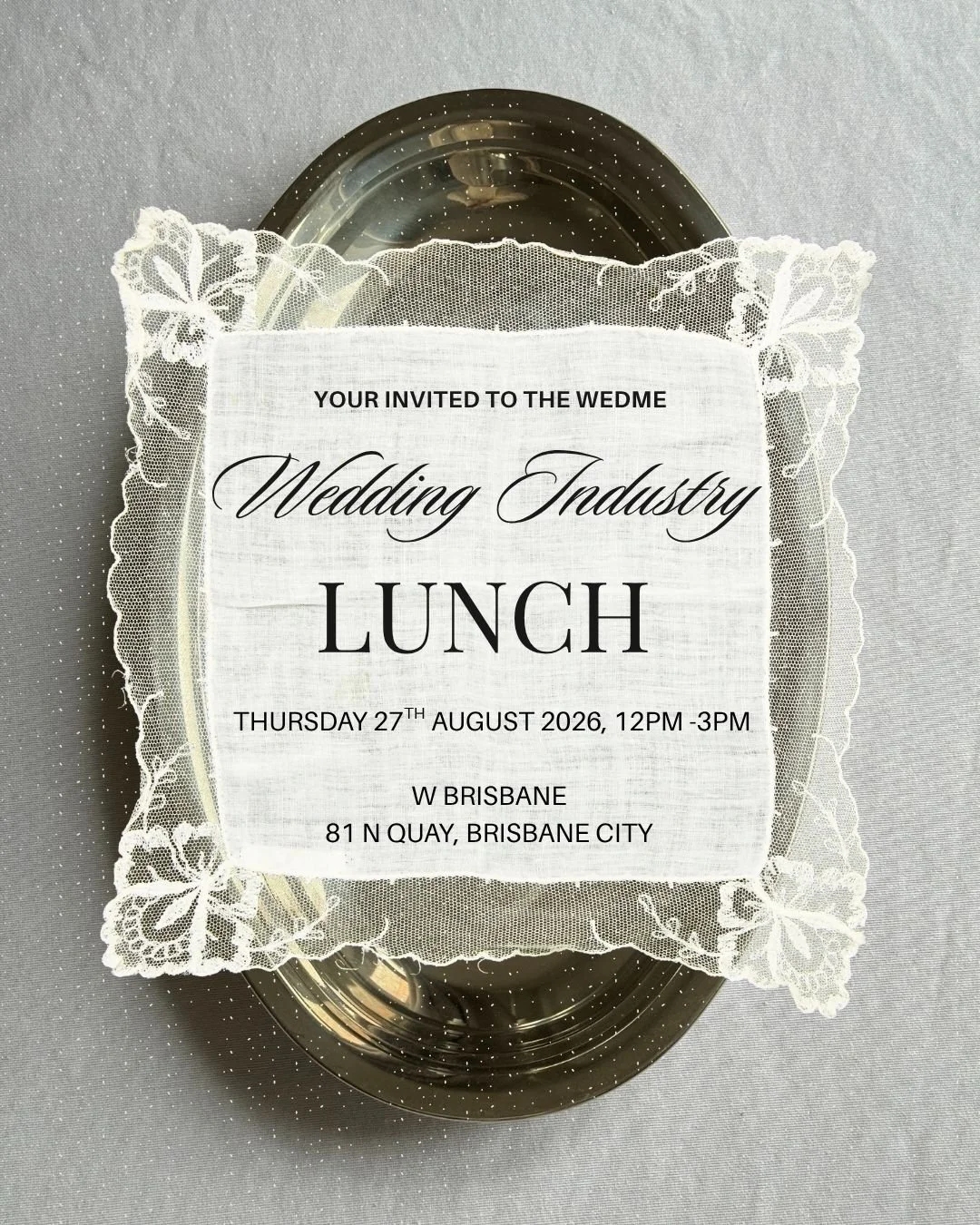 Invitation to a wedding industry lunch on Thursday, August 27, 2026, from 12 PM to 3 PM at W Brisbane, 81 N Quay, Brisbane City. The invitation is displayed on a metallic tray with a lace doily.