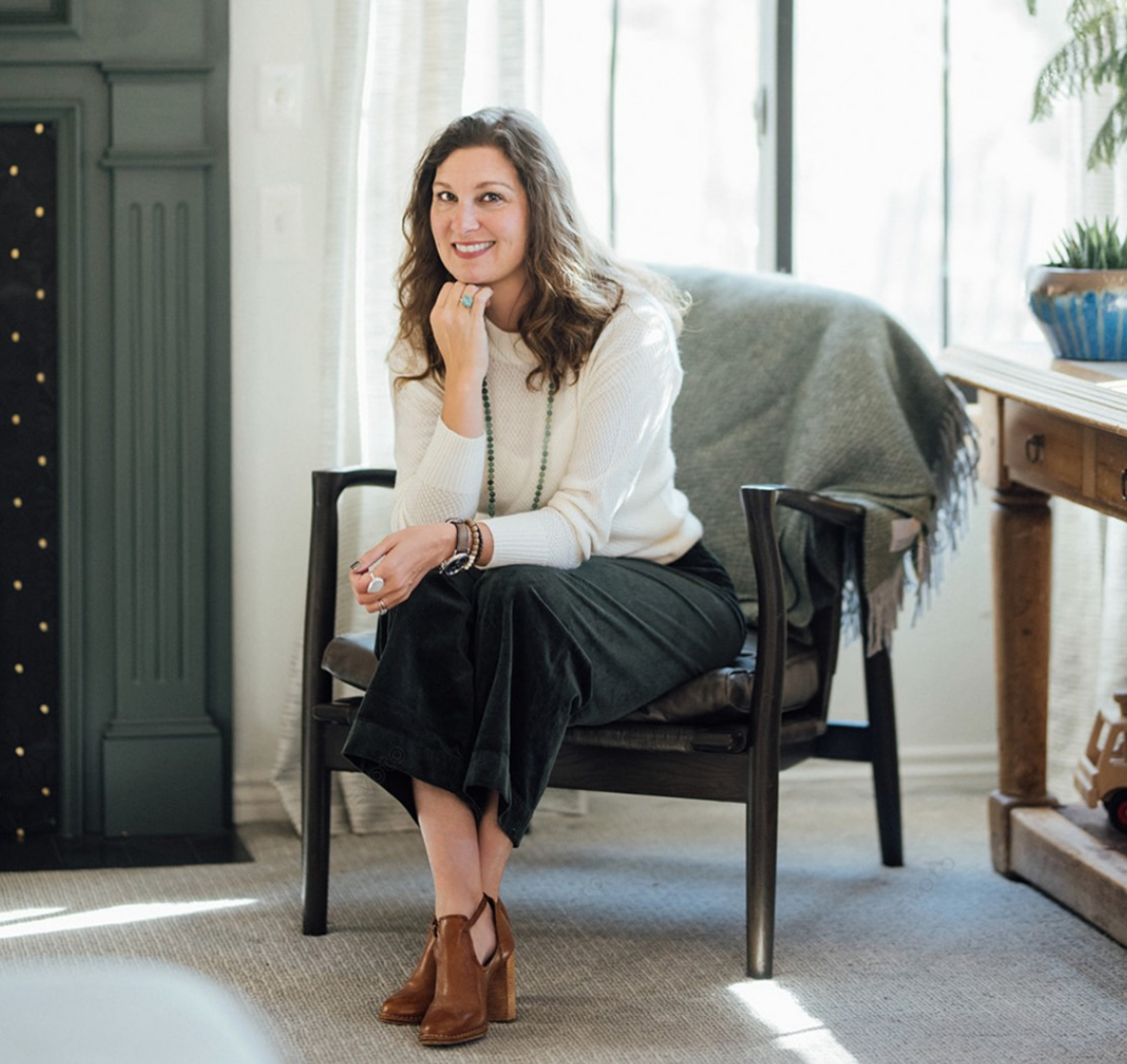 woman sitting on chair with white sweater and dark green pants