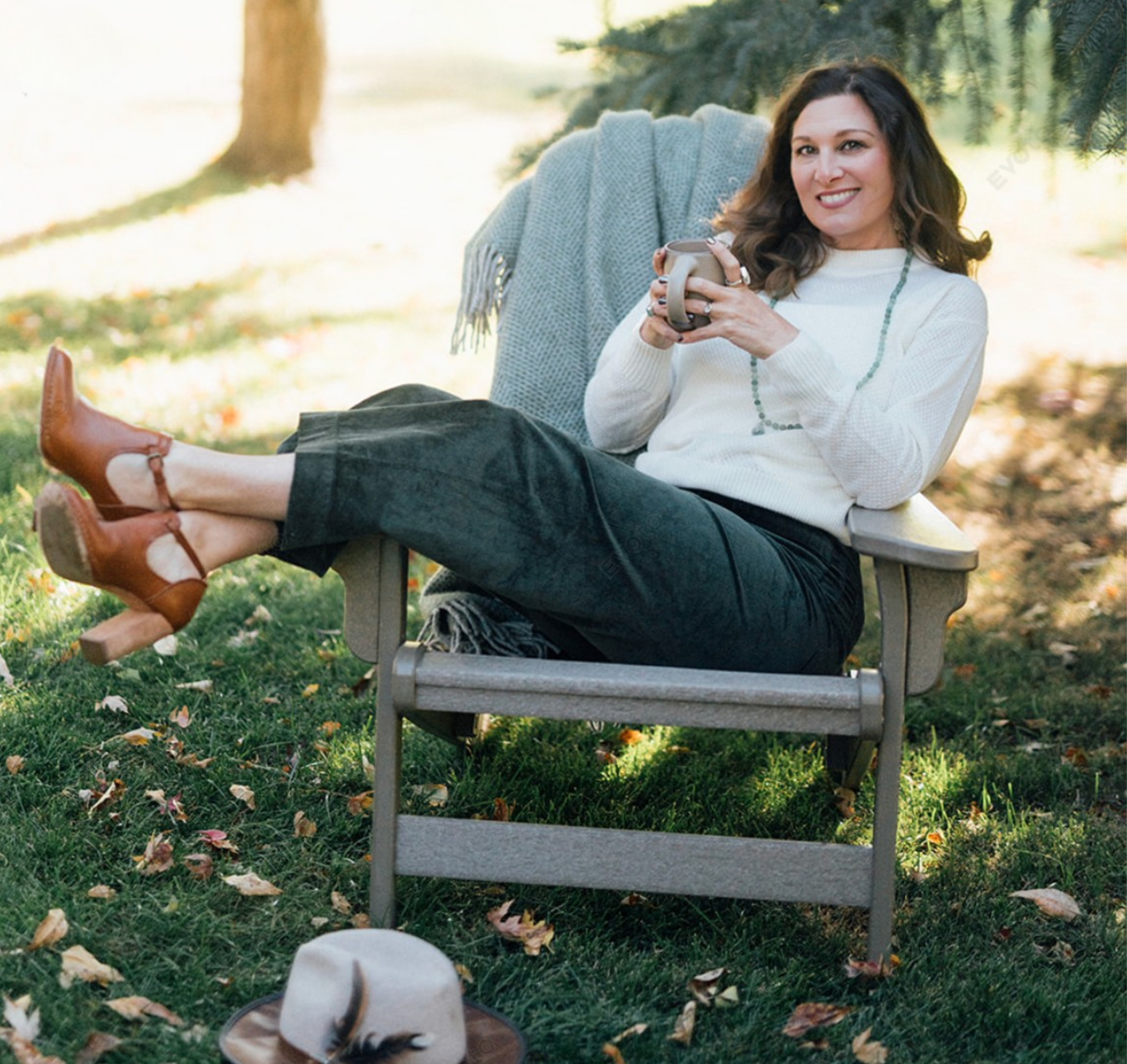 woman in chair outdoors with coffee mug and smiling