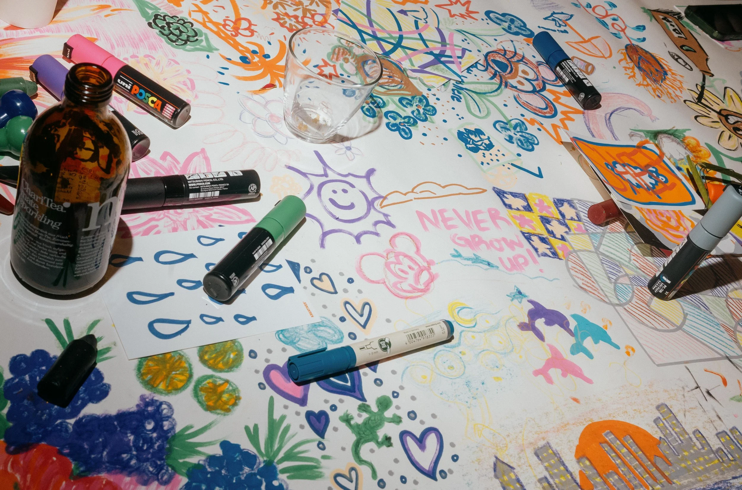 Colorful drawings, markers, and art supplies scattered on a table.