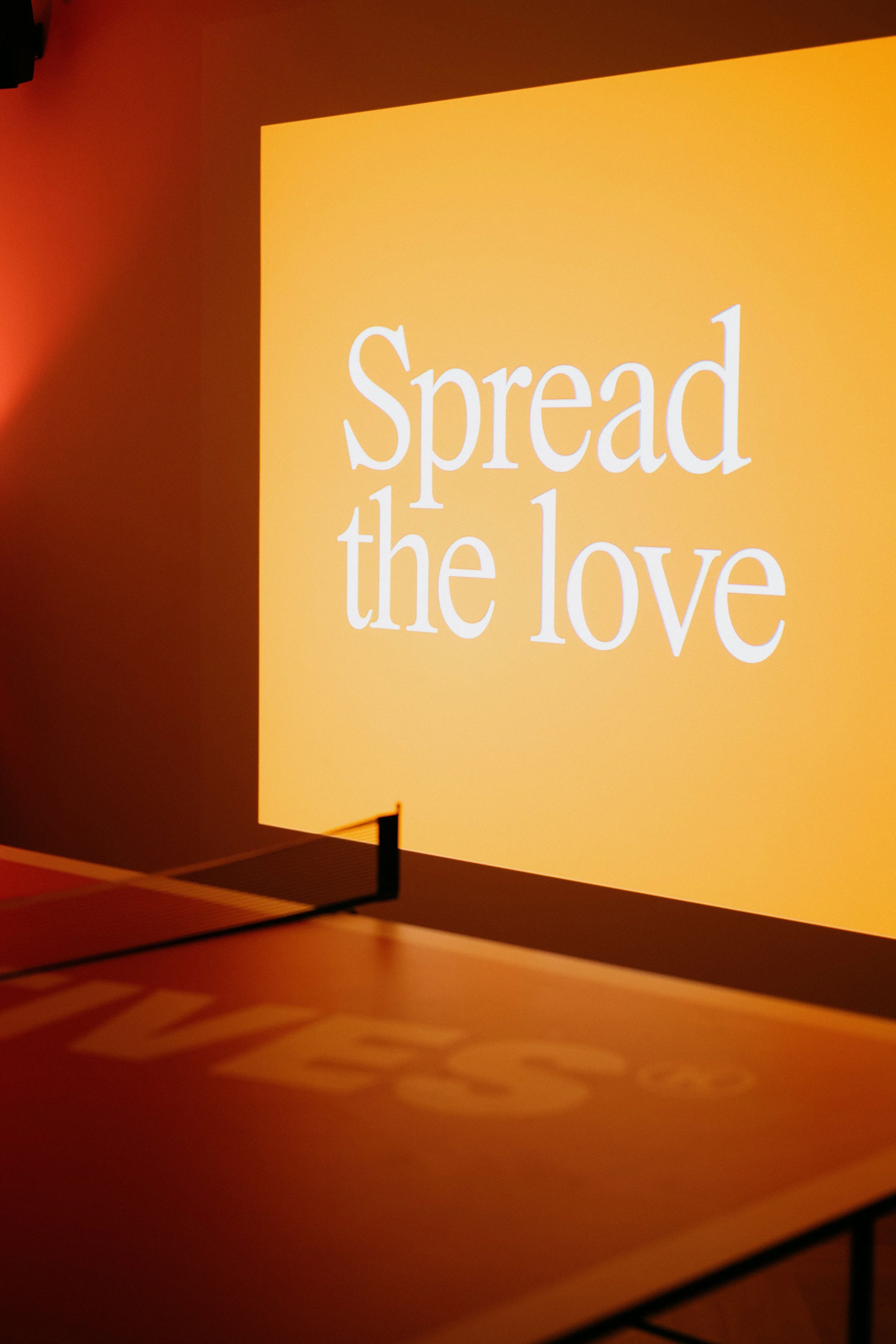 A projection screen displaying the message 'Spread the love' in white text on an orange background.