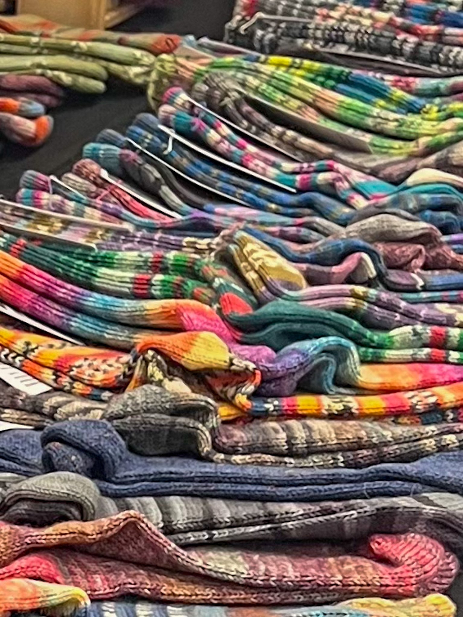 A large display of colorful patterned socks arranged in rows on a table at a store.