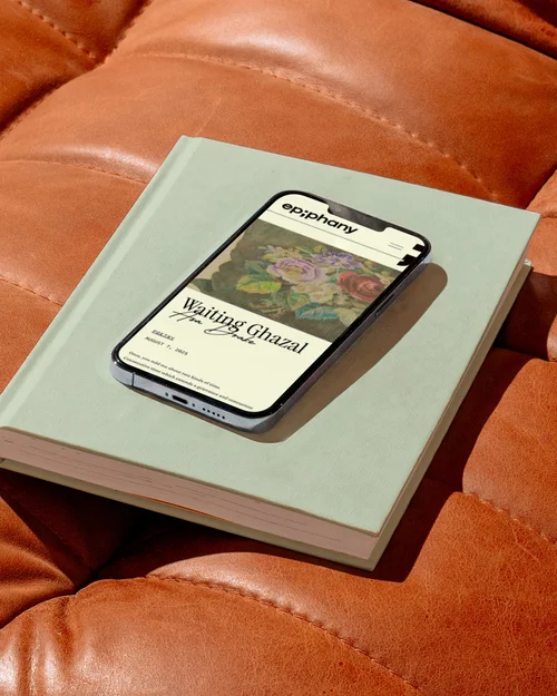 A phone showing the Epiphany website, resting on a book on an orange leather sofa