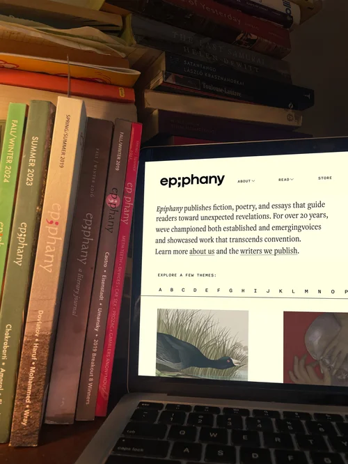 Laptop showing the Epiphany website, on a bookshelf