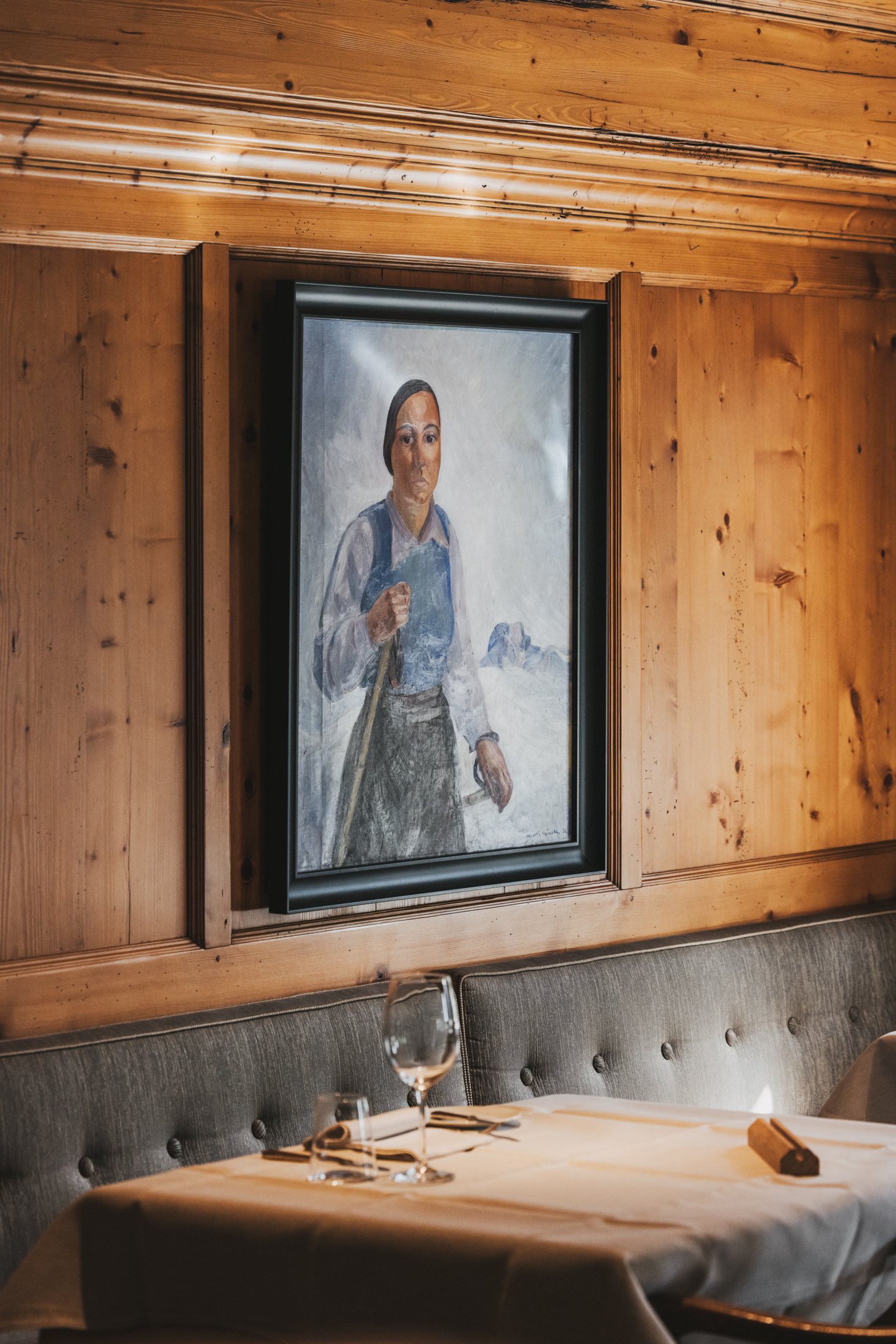 Öl-Gemälde von Maria Burger auf Skiern in den 1930er Jahren an der Wand. Im Vordergrund ein gedeckter Mittagstisch in gediegener Atmosphäre.