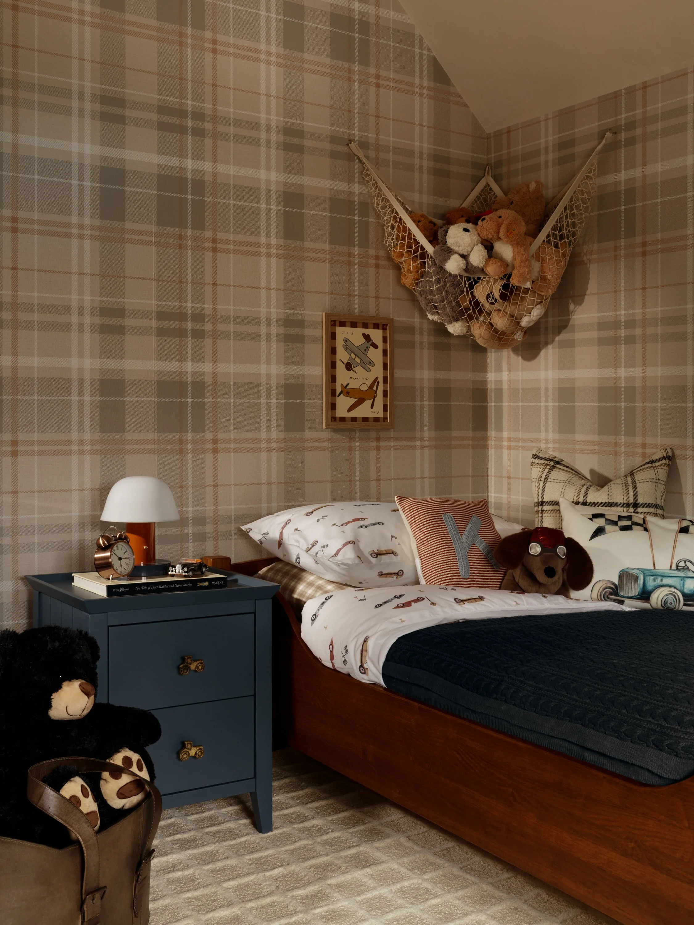 Walnut single bed against plaid wallpaper in heritage-inspired boy’s bedroom in Buckinghamshire.