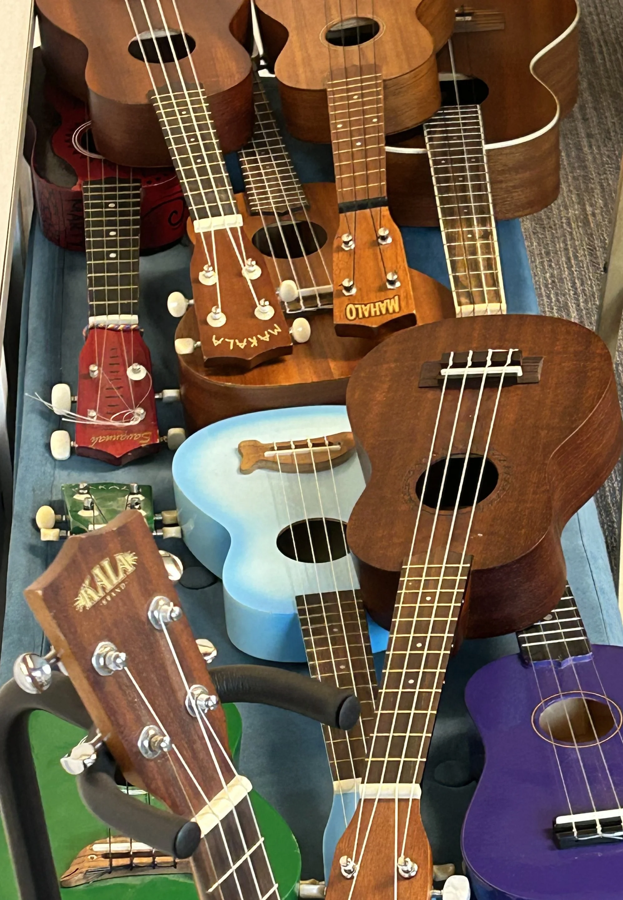 several multicolored ukeleles stacked on top of eachother