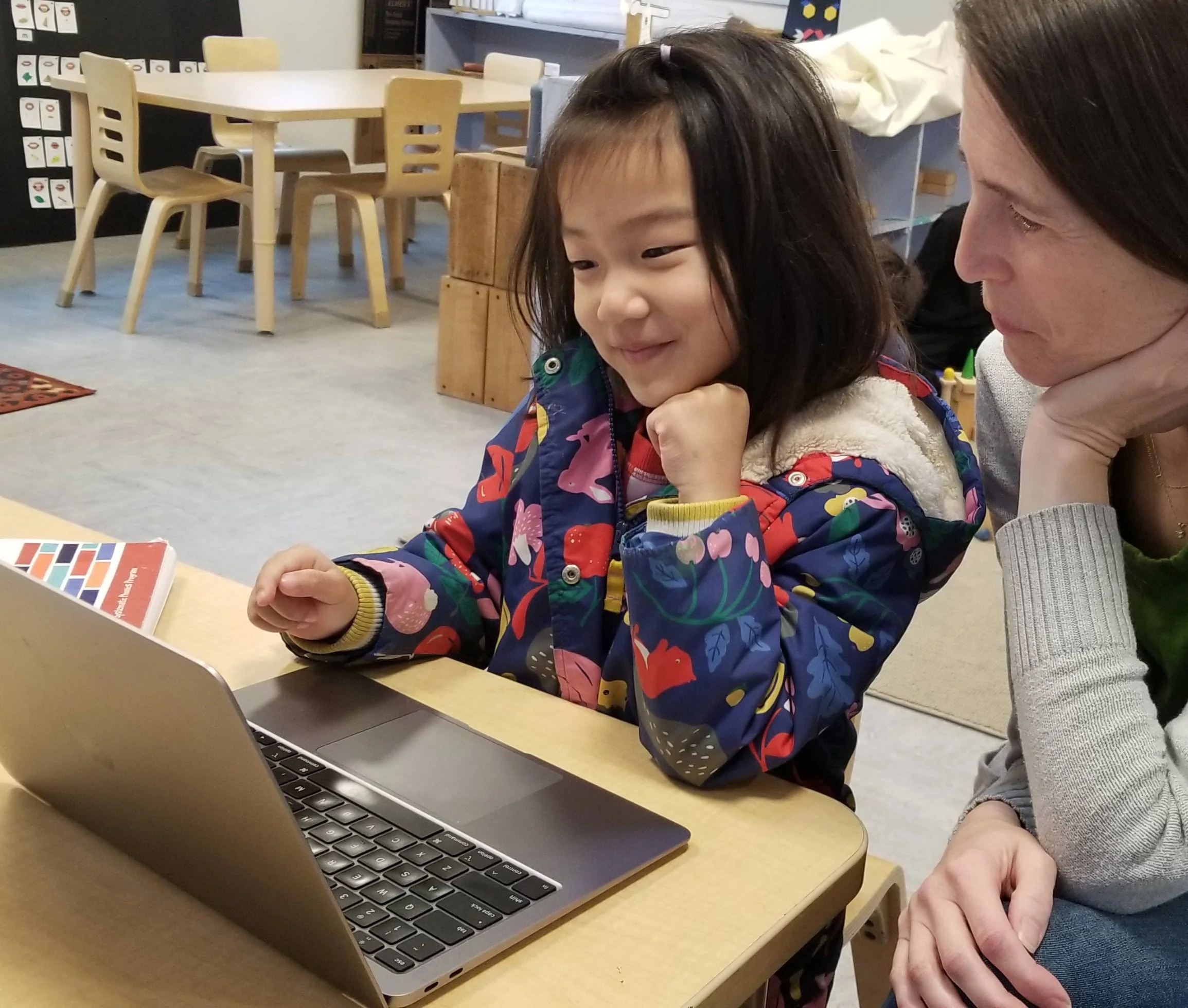 one teacher partially hidden, and one student looking at a computer in a classroom