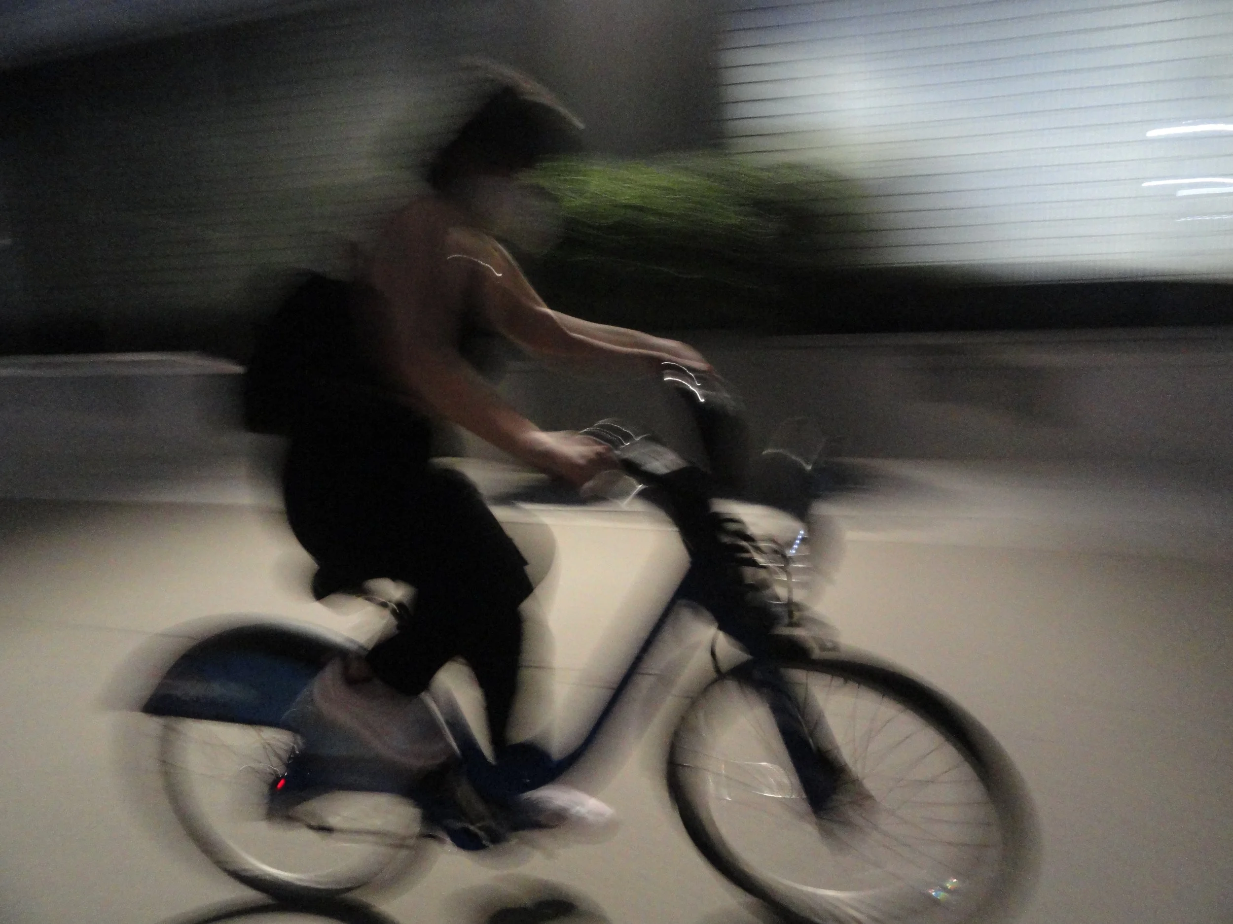 A person riding a bicycle at night with motion blur.