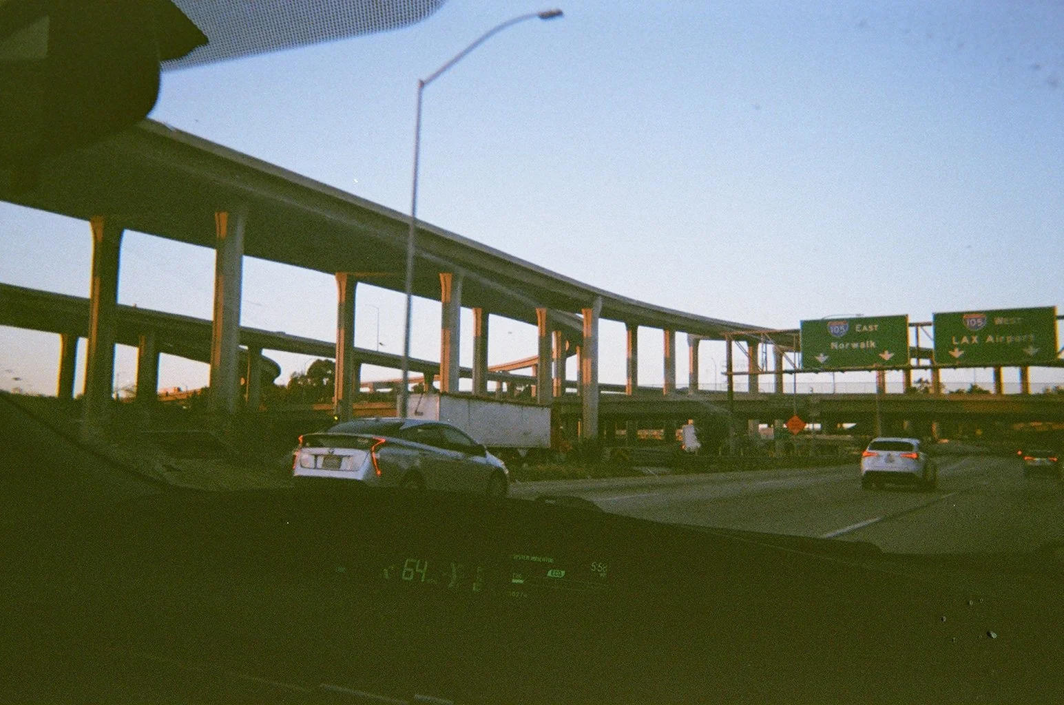 View of a highway interchange with overpasses, cars traveling, and signage for East Norwalk and Lax Airport on a clear day.