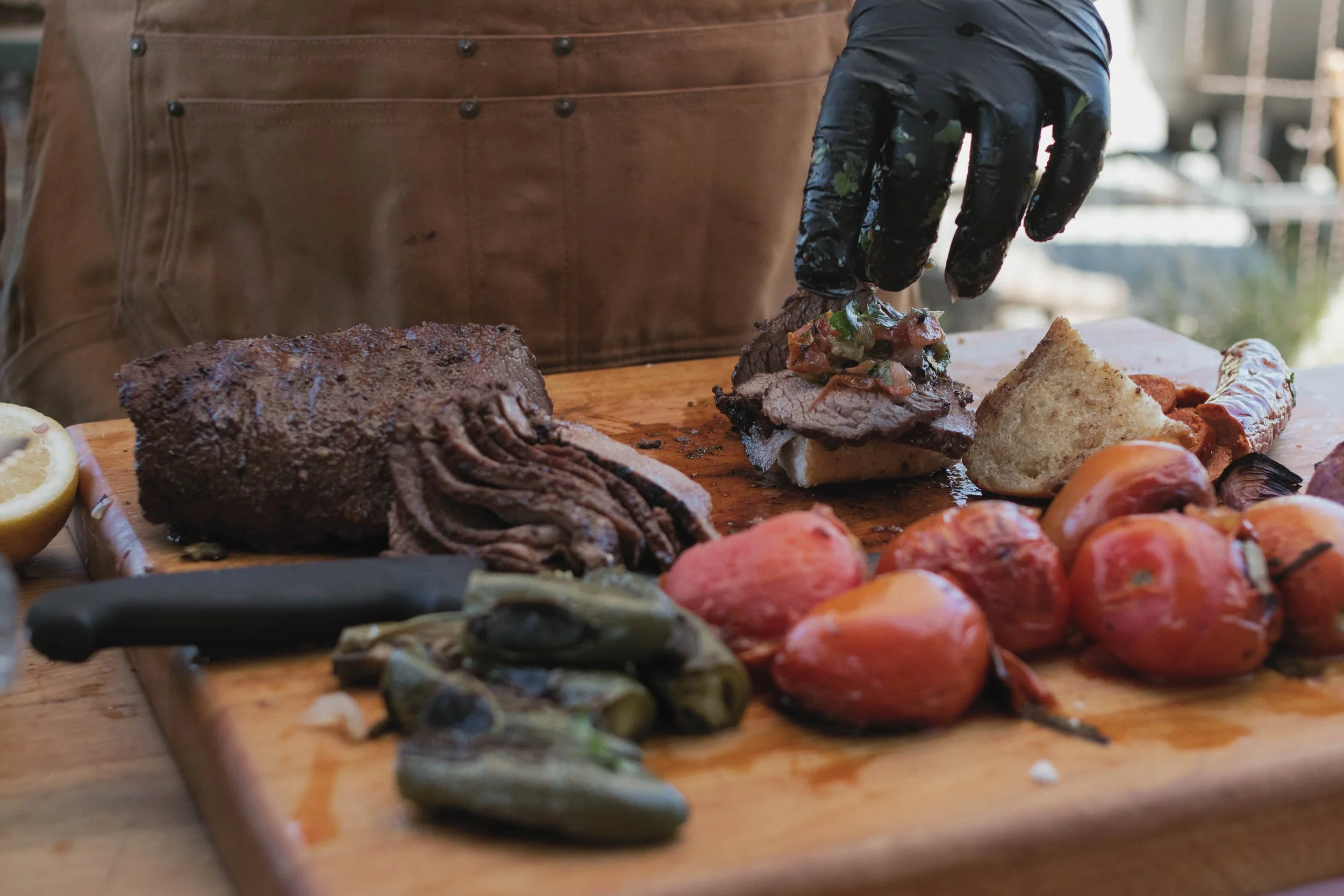 Chef puts tri-tip slices on french roll and tops with fresh salsa