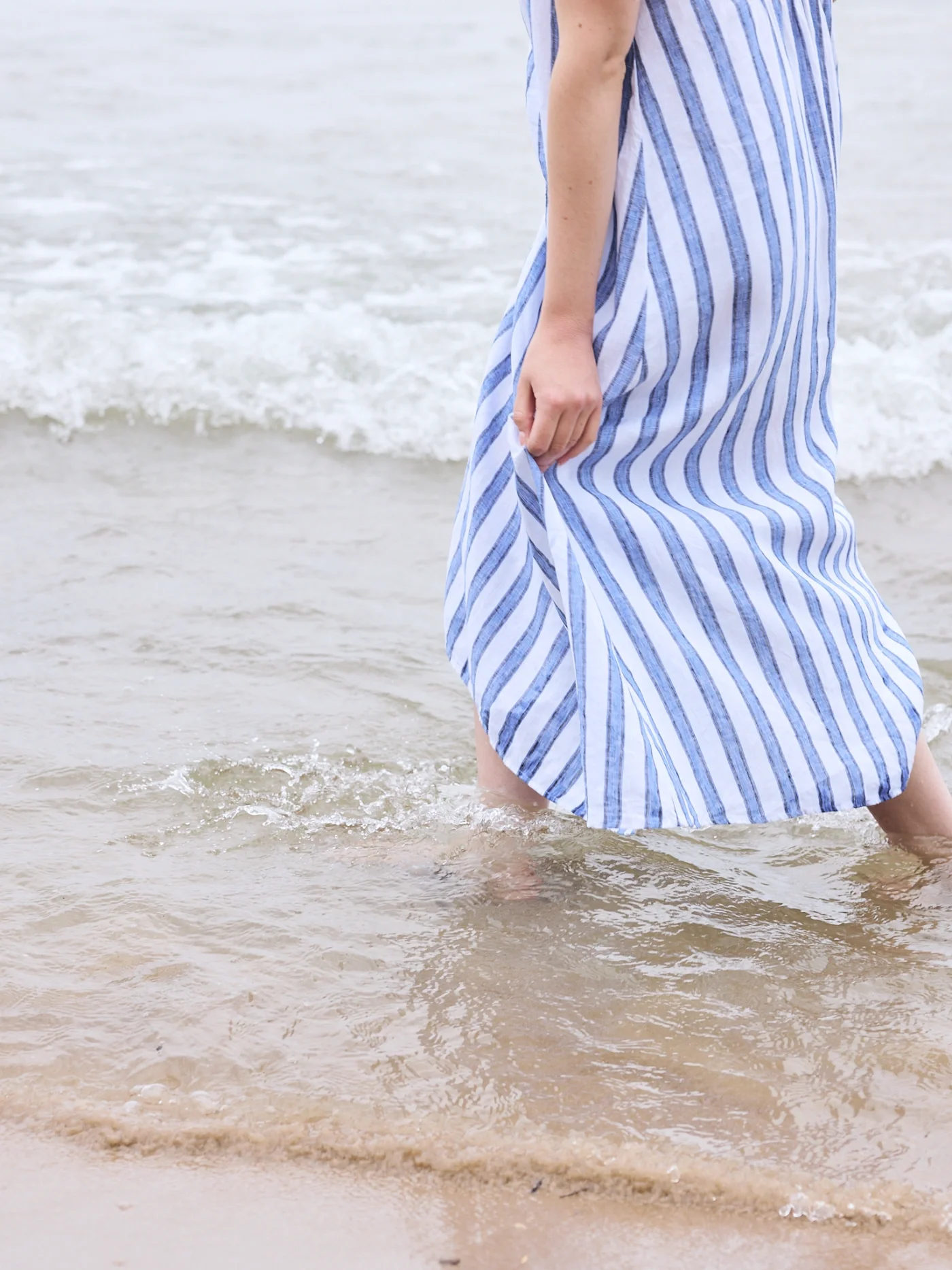 Taylor of With Ease Therapy Space in Guelph wading in a lake in a long, blue and white dress.