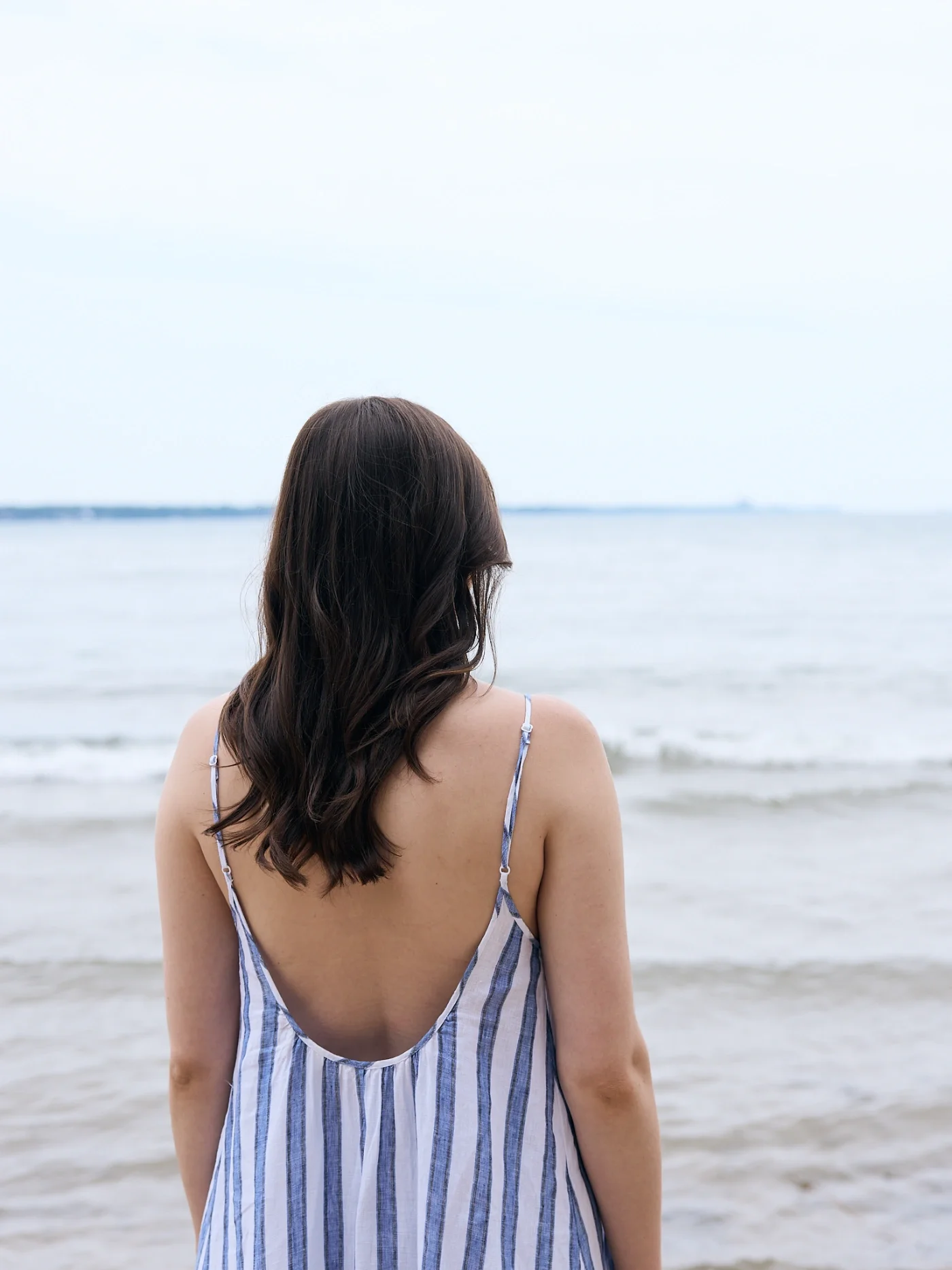 Taylor of With Ease Therapy Space in Guelph standing on a beach facing the lake.