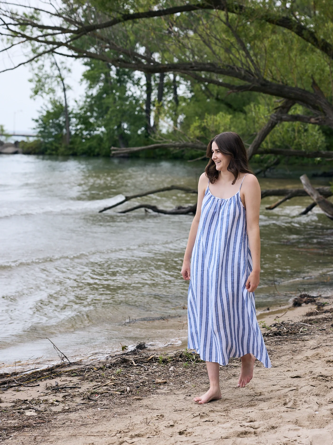 Taylor of With Ease Therapy Space in Guelph walking barefoot on a sandy beach by a lake.