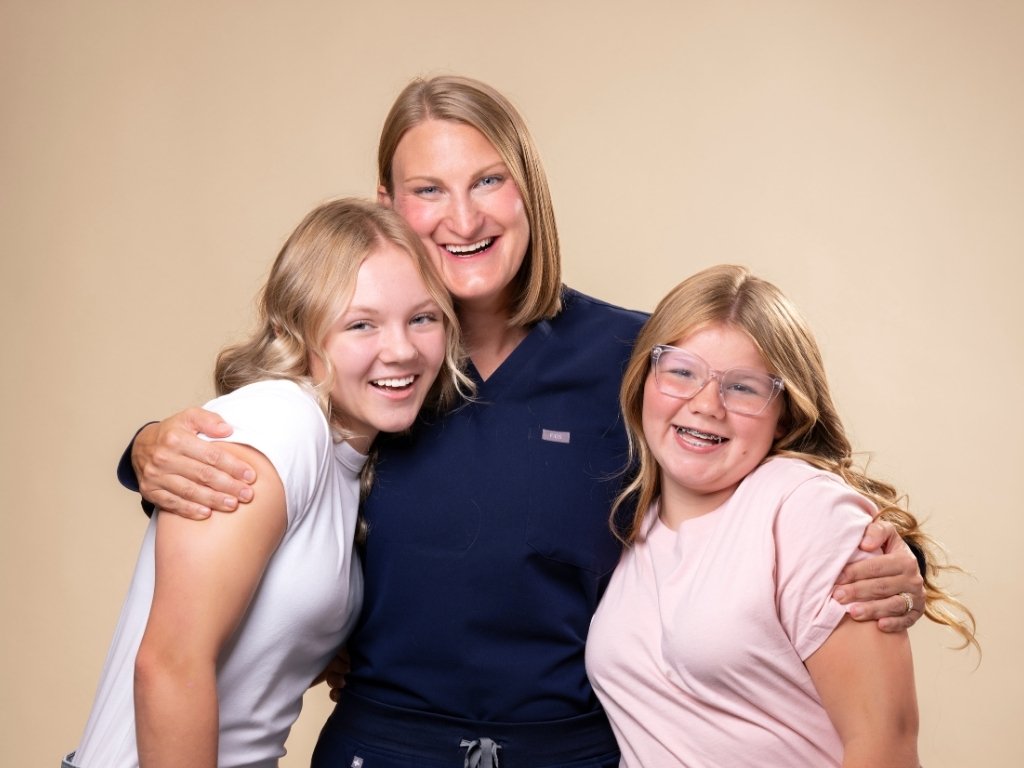 Dr. Emily Willett embracing two orthodontic patients