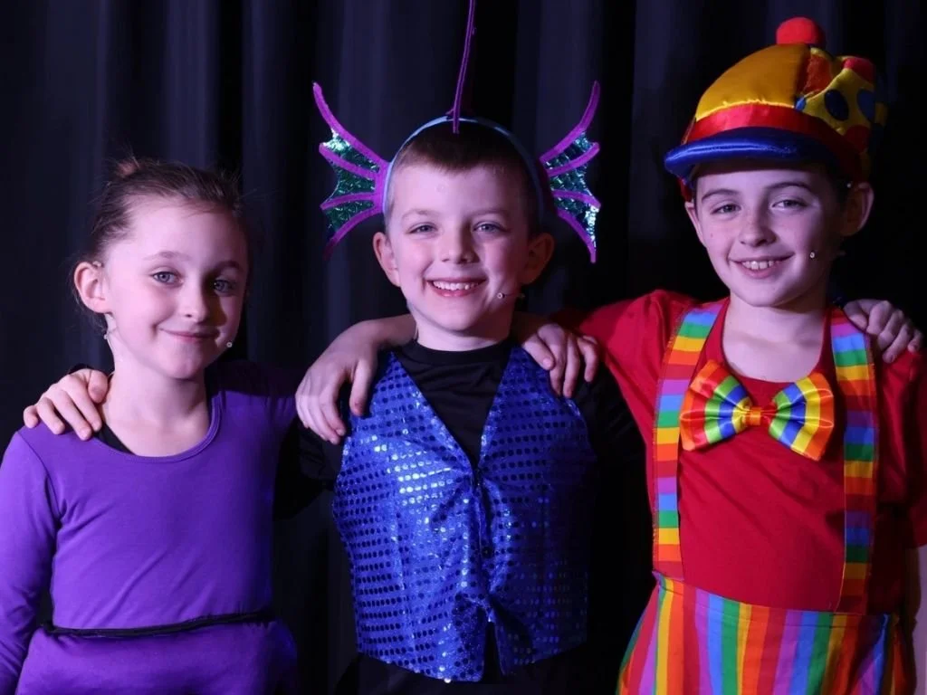 Three young children theatre actors dressed in colorful costumes