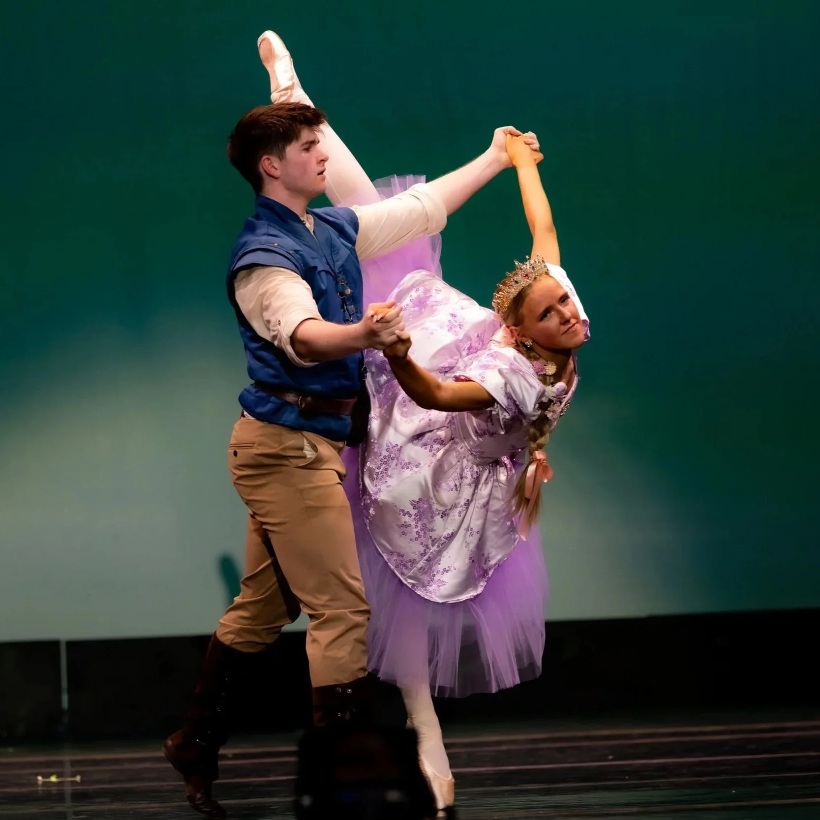 Man and woman dancing on stage in Rapunzel and Flynn Rider costumes