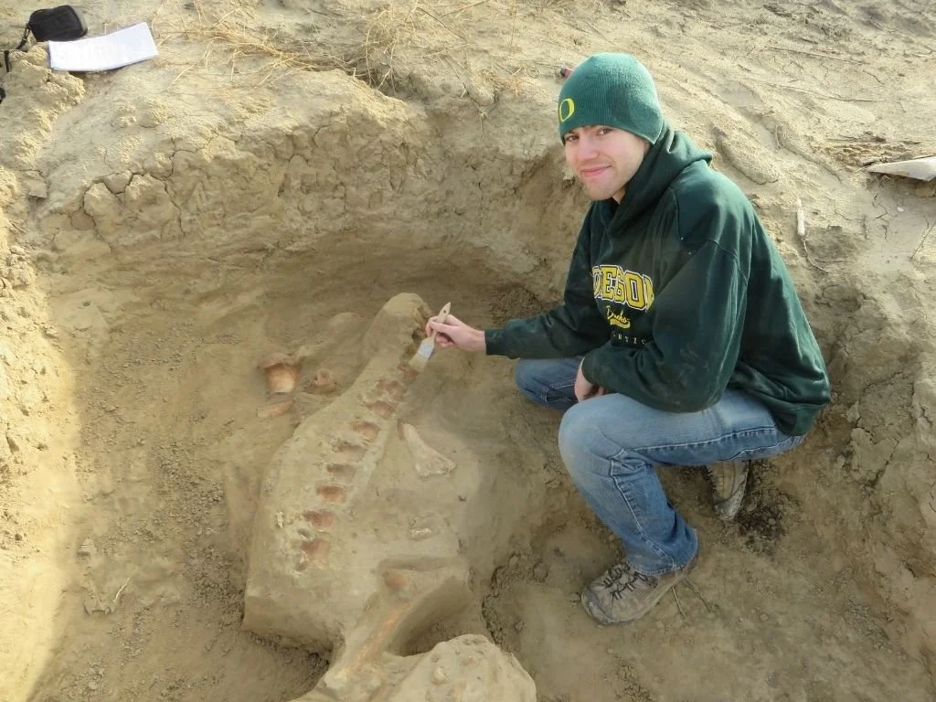 Jeremy in dirt uncovering fossill